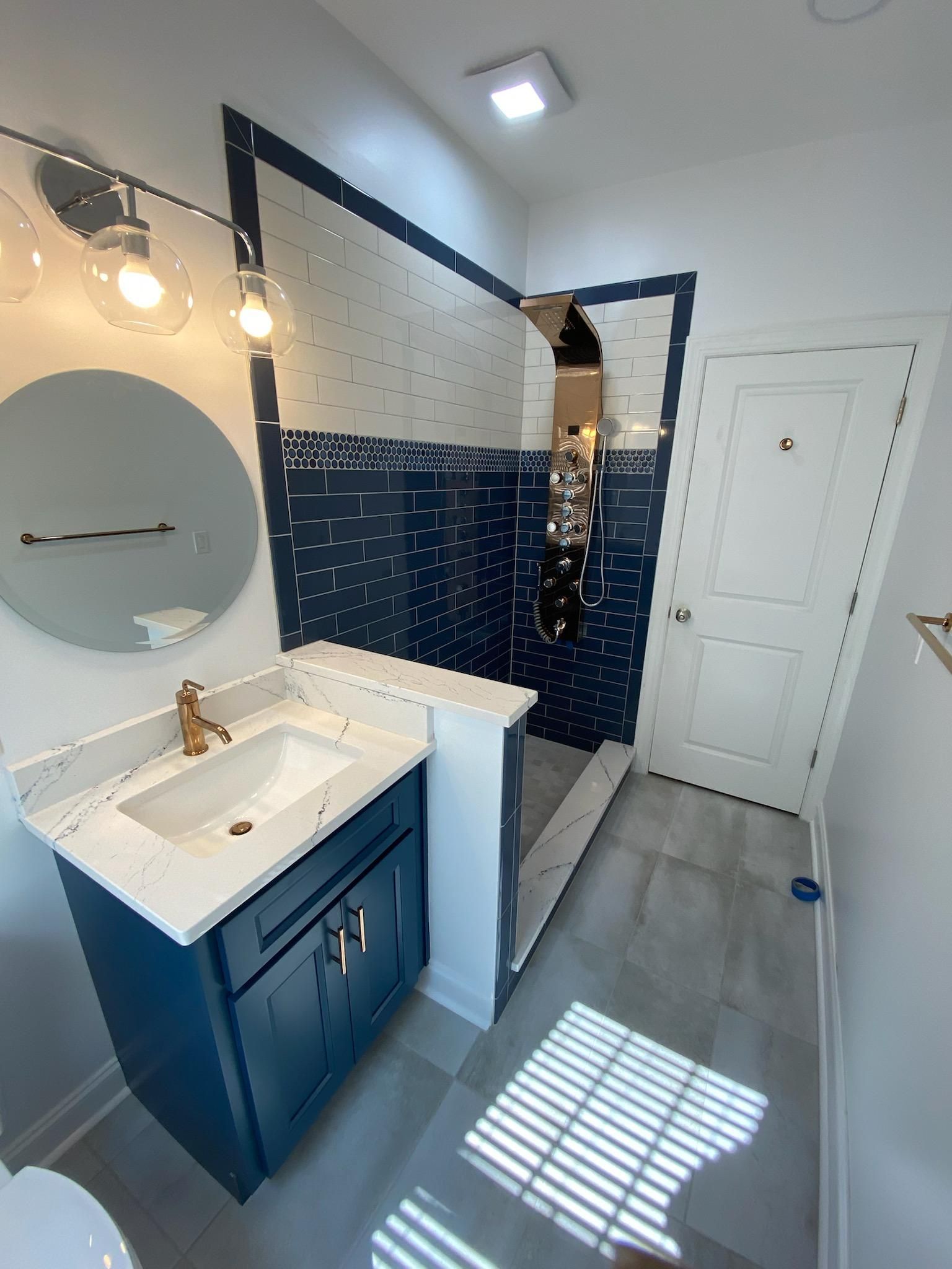 A bathroom with a sink , toilet , mirror and walk in shower.