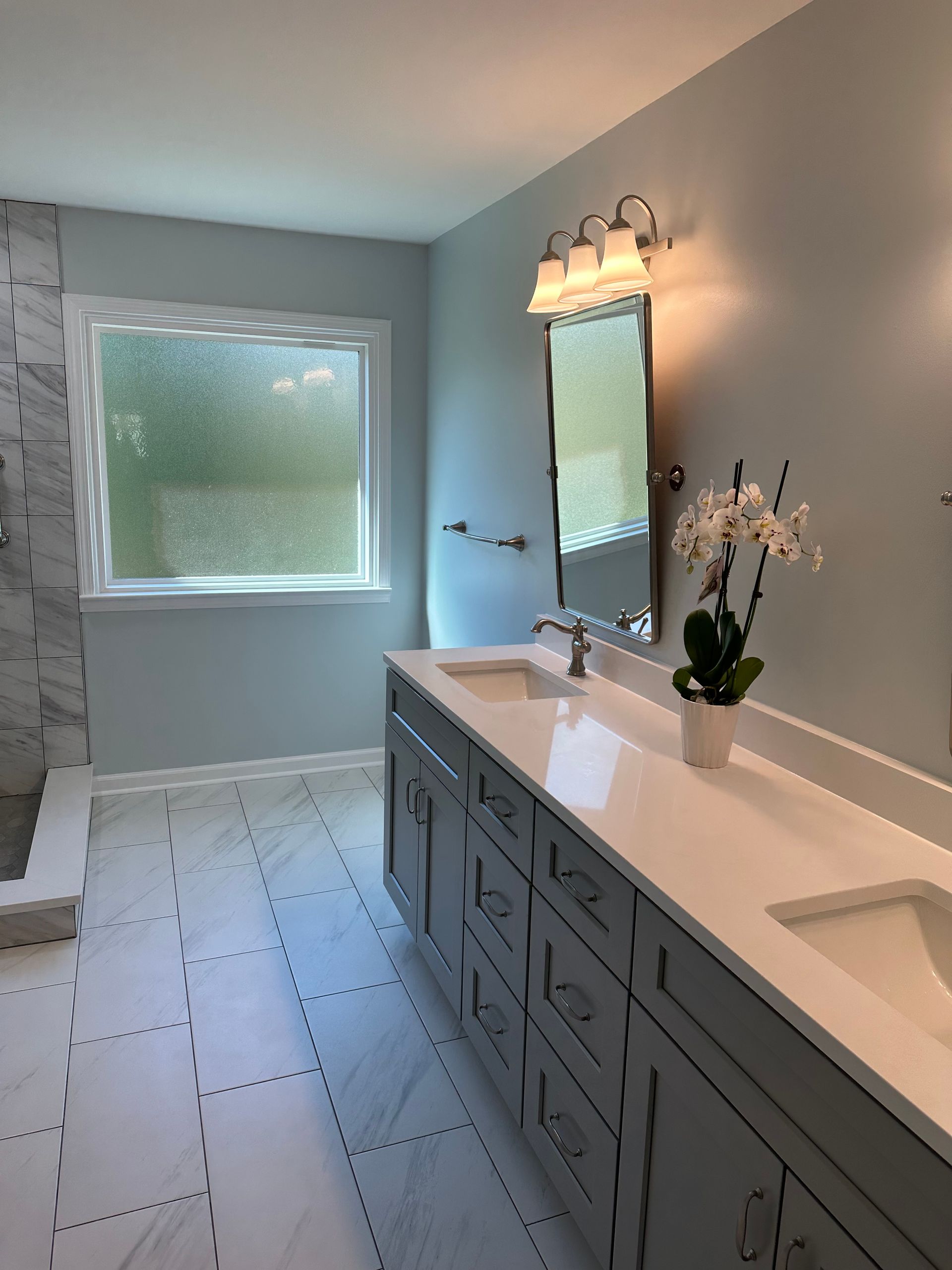 A bathroom with two sinks , a mirror and a window