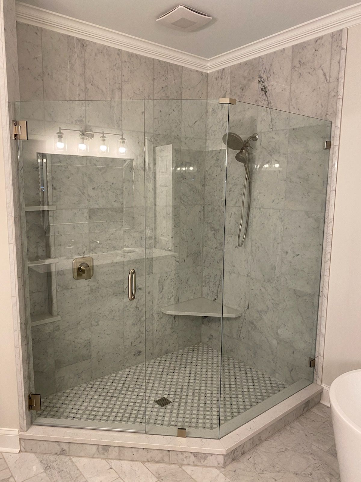 A bathroom with a walk in shower with a glass door.