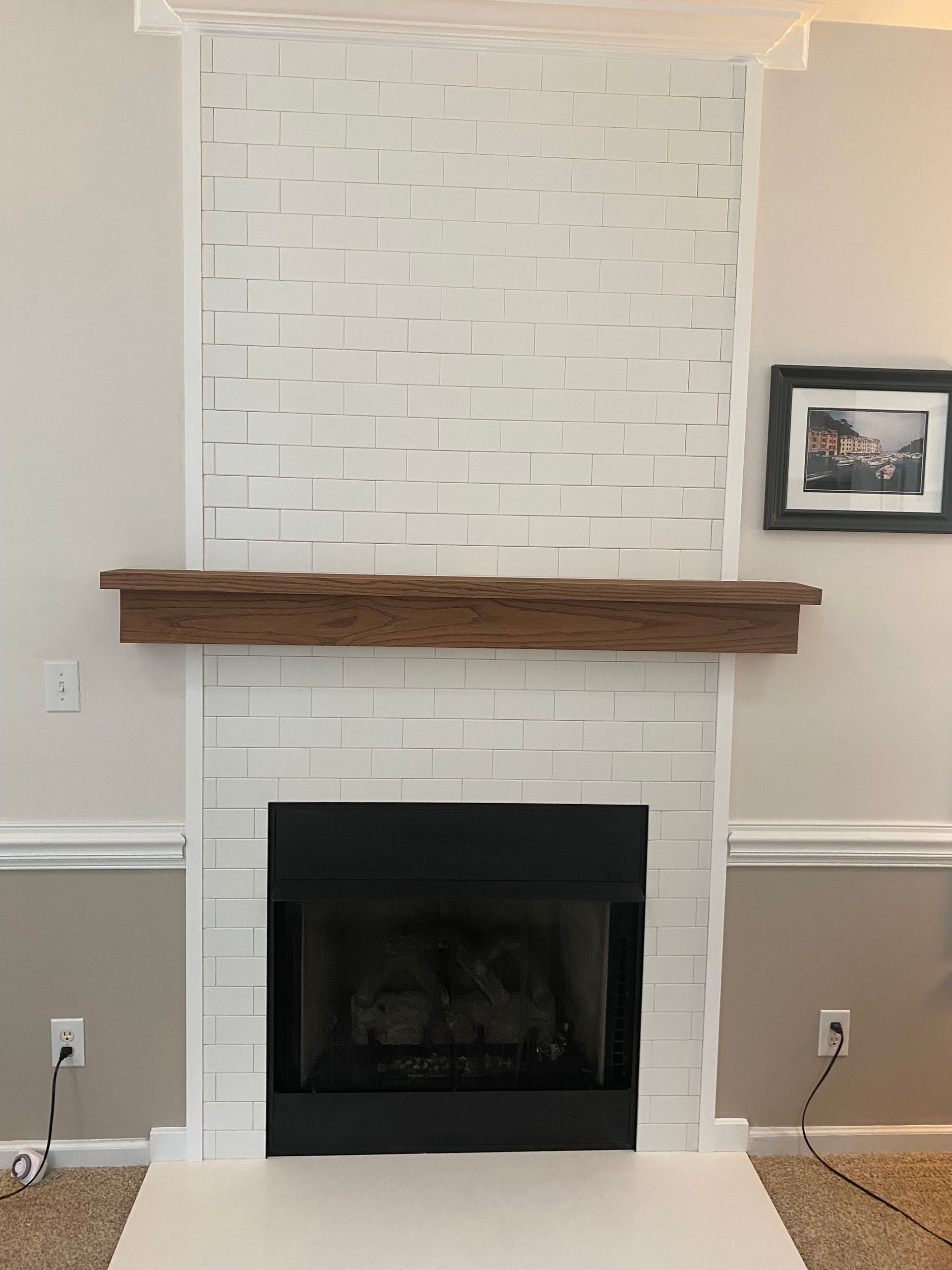 A white brick fireplace with a wooden mantle in a living room.