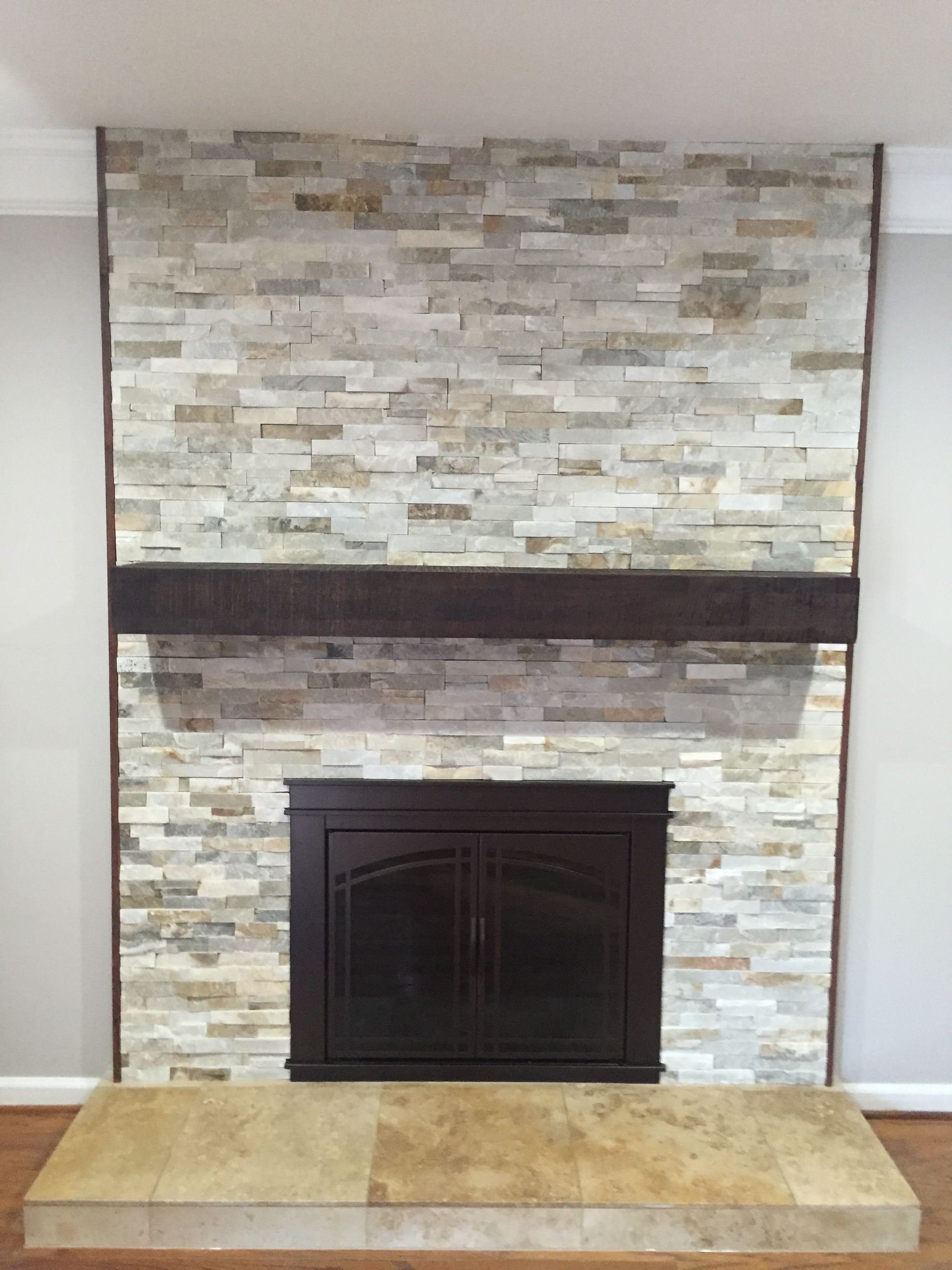 A fireplace with a stone wall and a wooden mantle