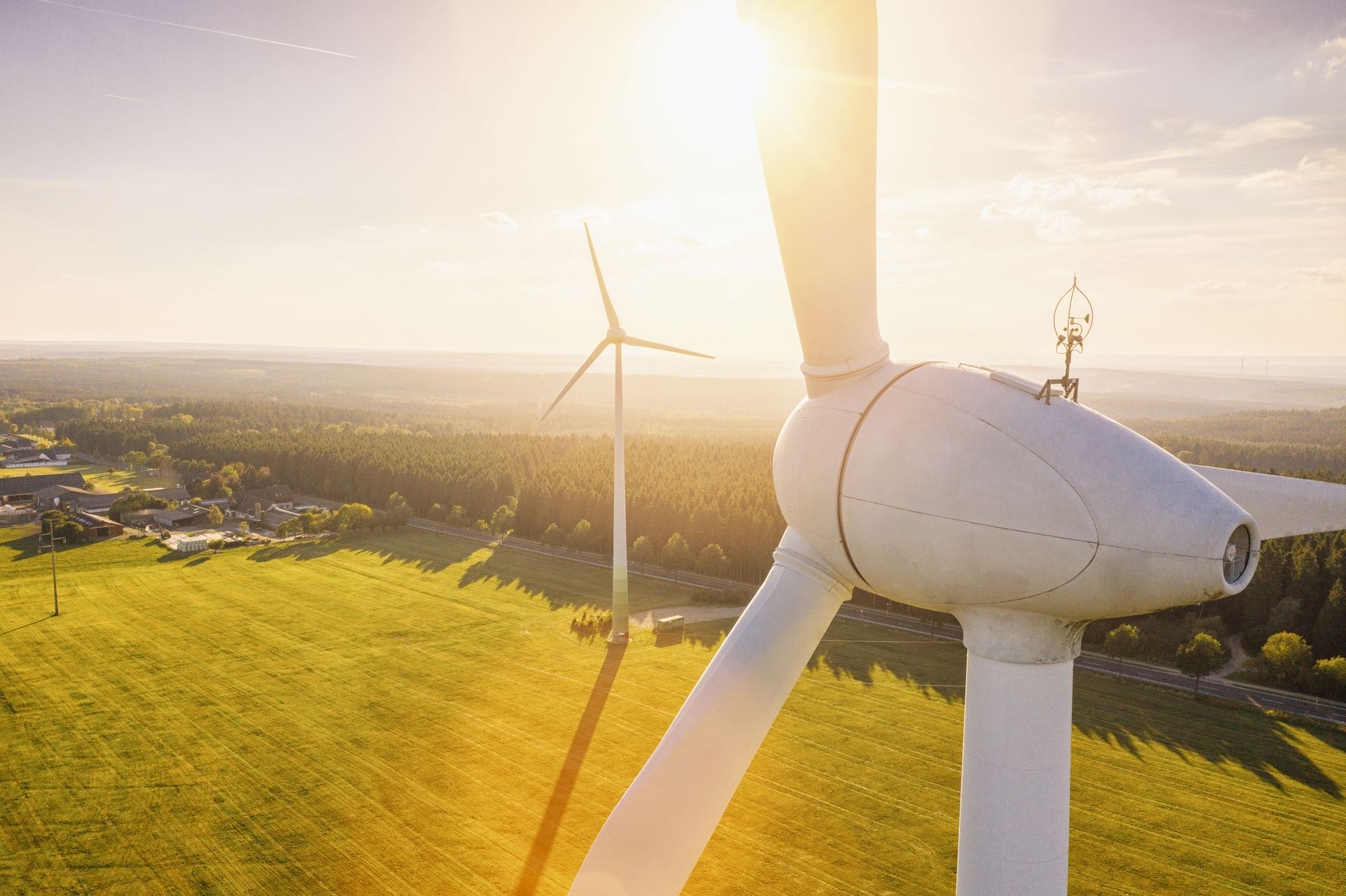Wind turbines in a sunlit green field at sunset