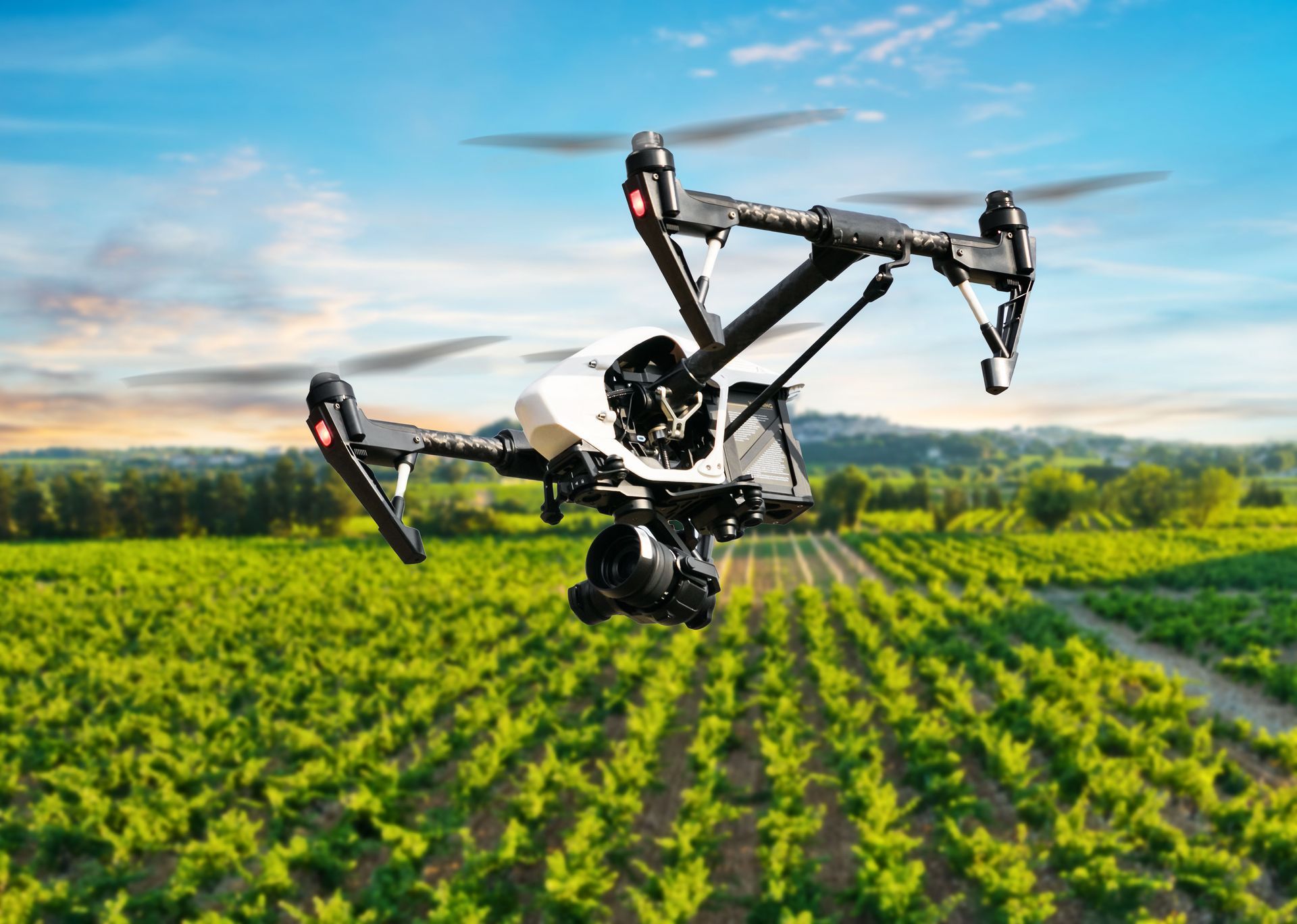 Agricultural drone spraying crops over a green field at sunset