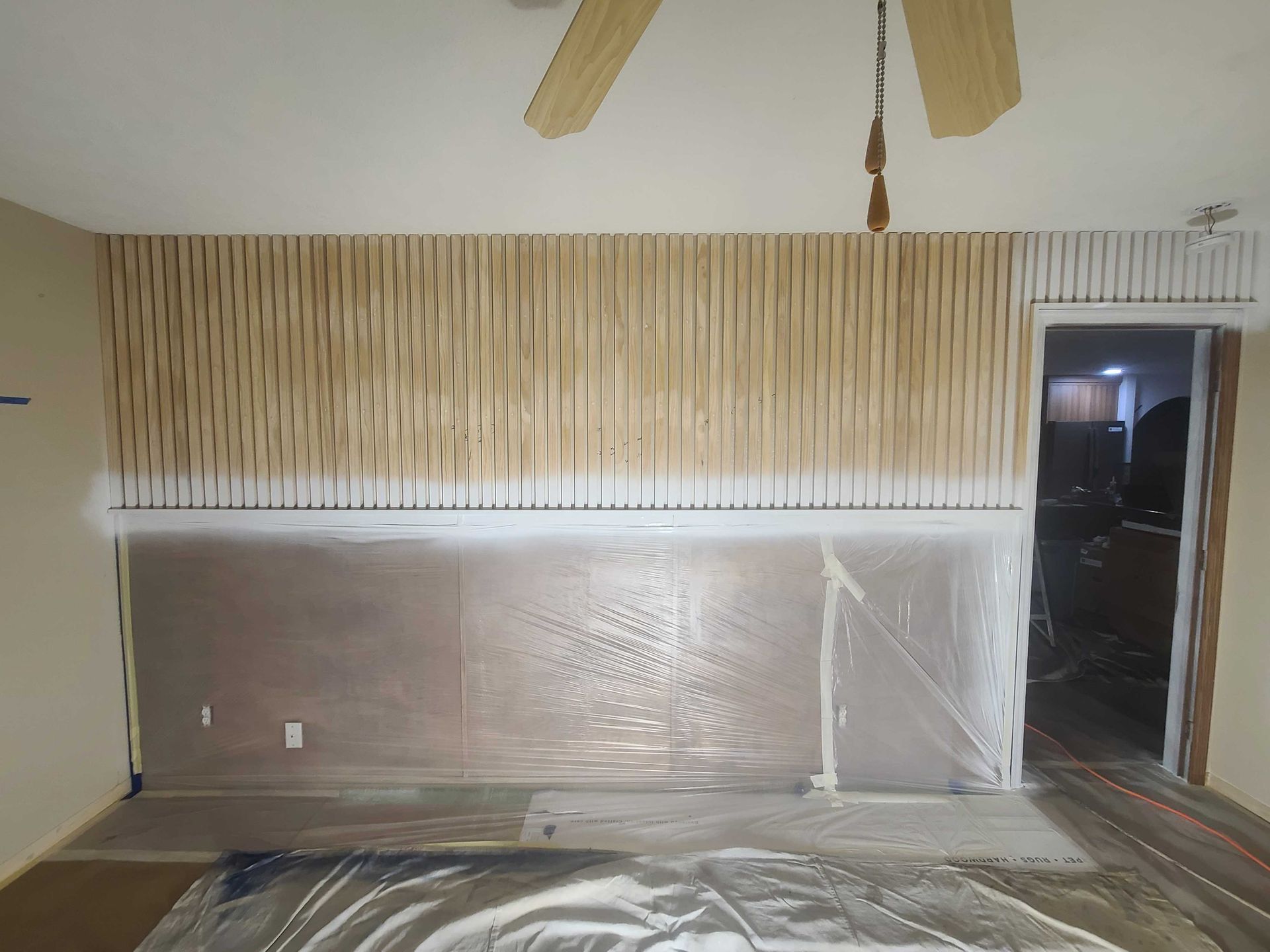 A room is being painted with a ceiling fan hanging from the ceiling.