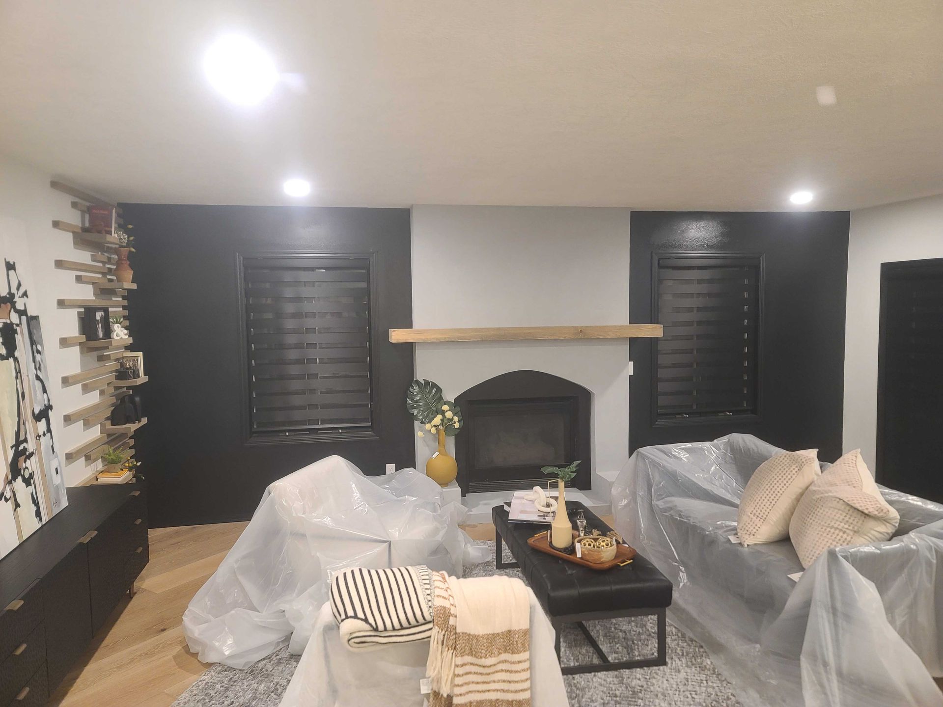 A living room with a fireplace and a couch covered in plastic.