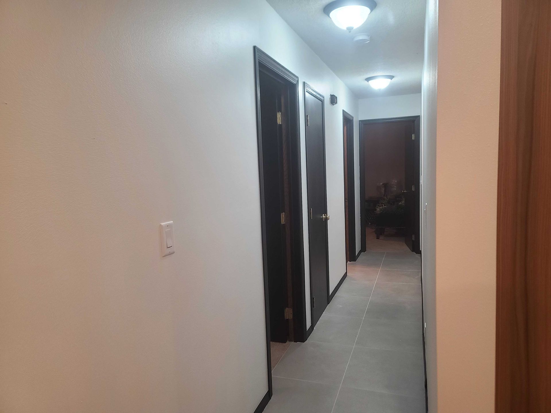 A long hallway with a lot of doors and a light on the ceiling.