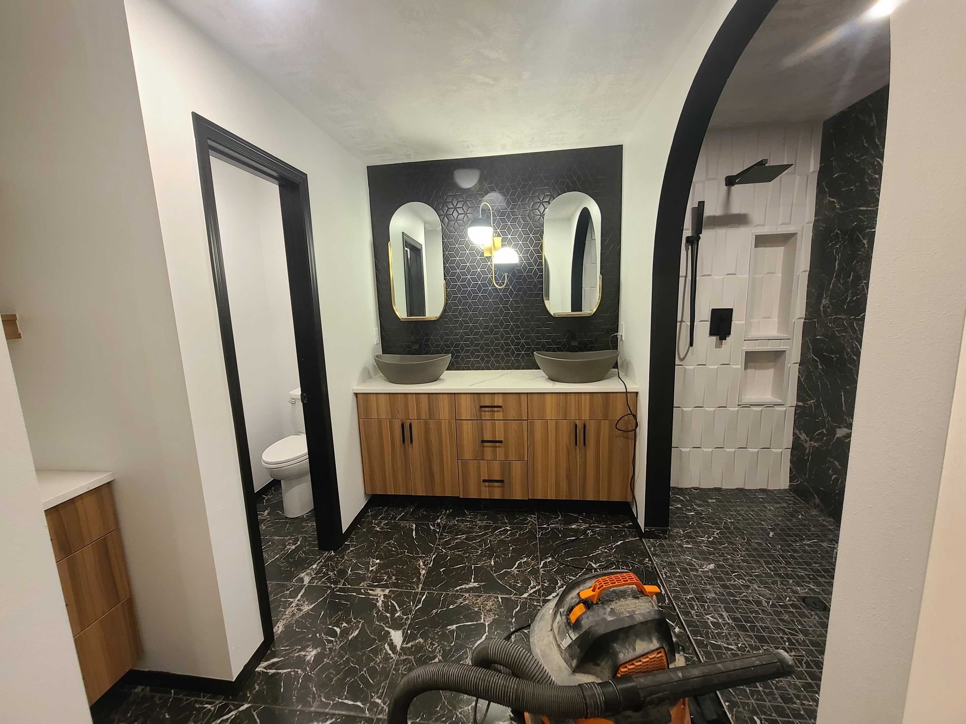 A bathroom with two sinks , a toilet and a vacuum cleaner.