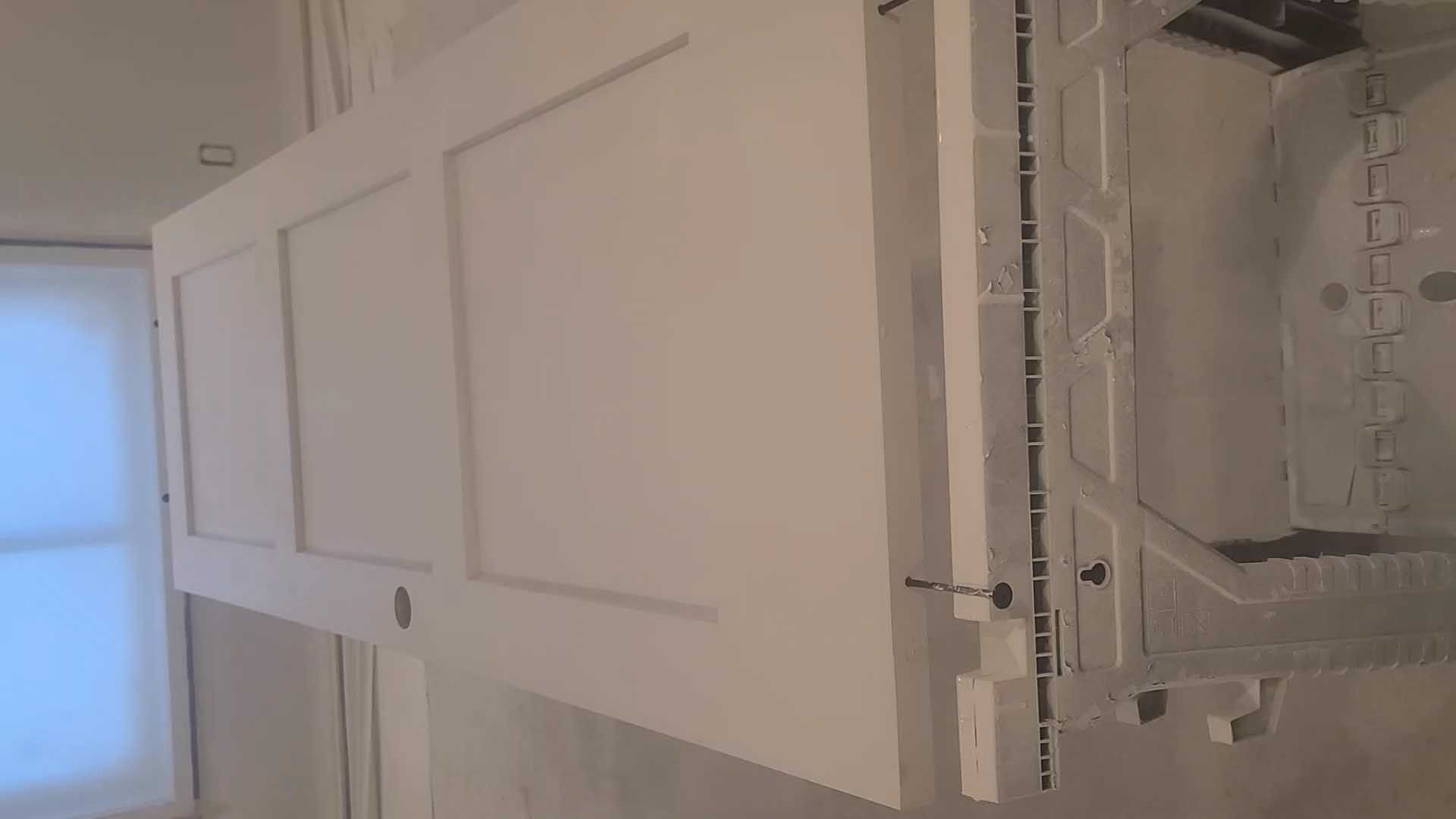 A white door is open in a room next to a window.