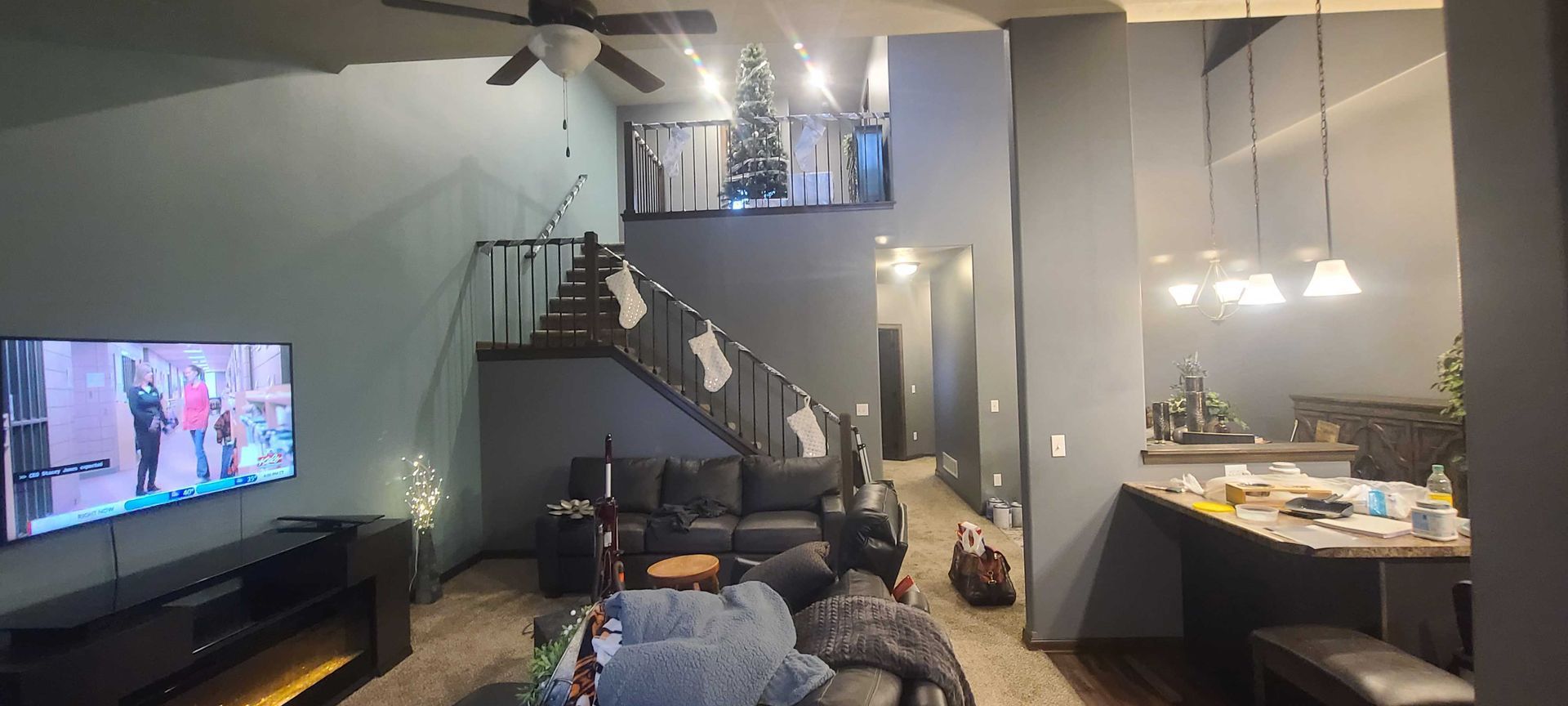A living room with a staircase and a flat screen tv.