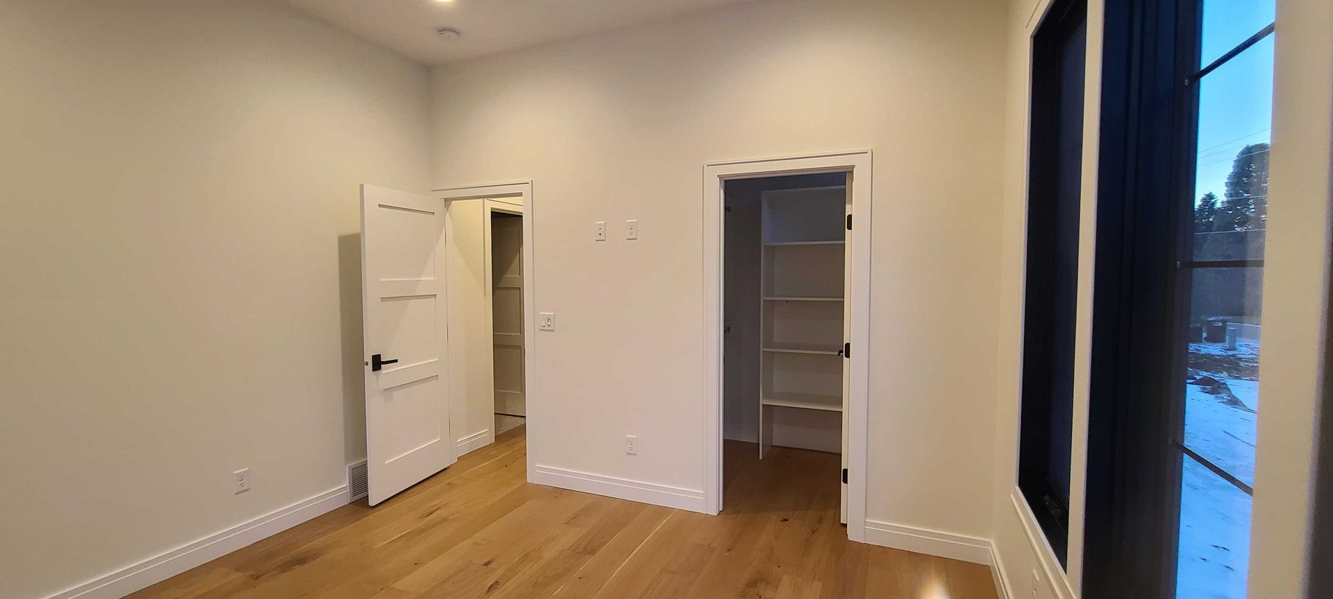 An empty bedroom with hardwood floors and a walk in closet.