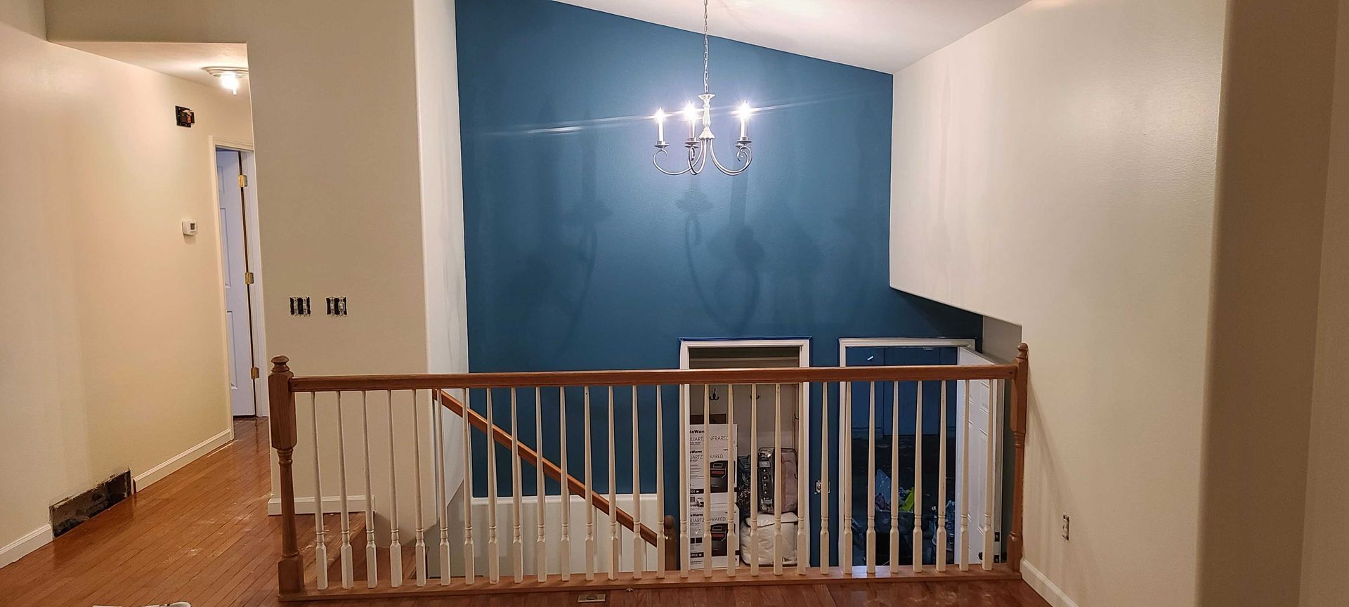 A living room with a blue wall , stairs , and a chandelier.