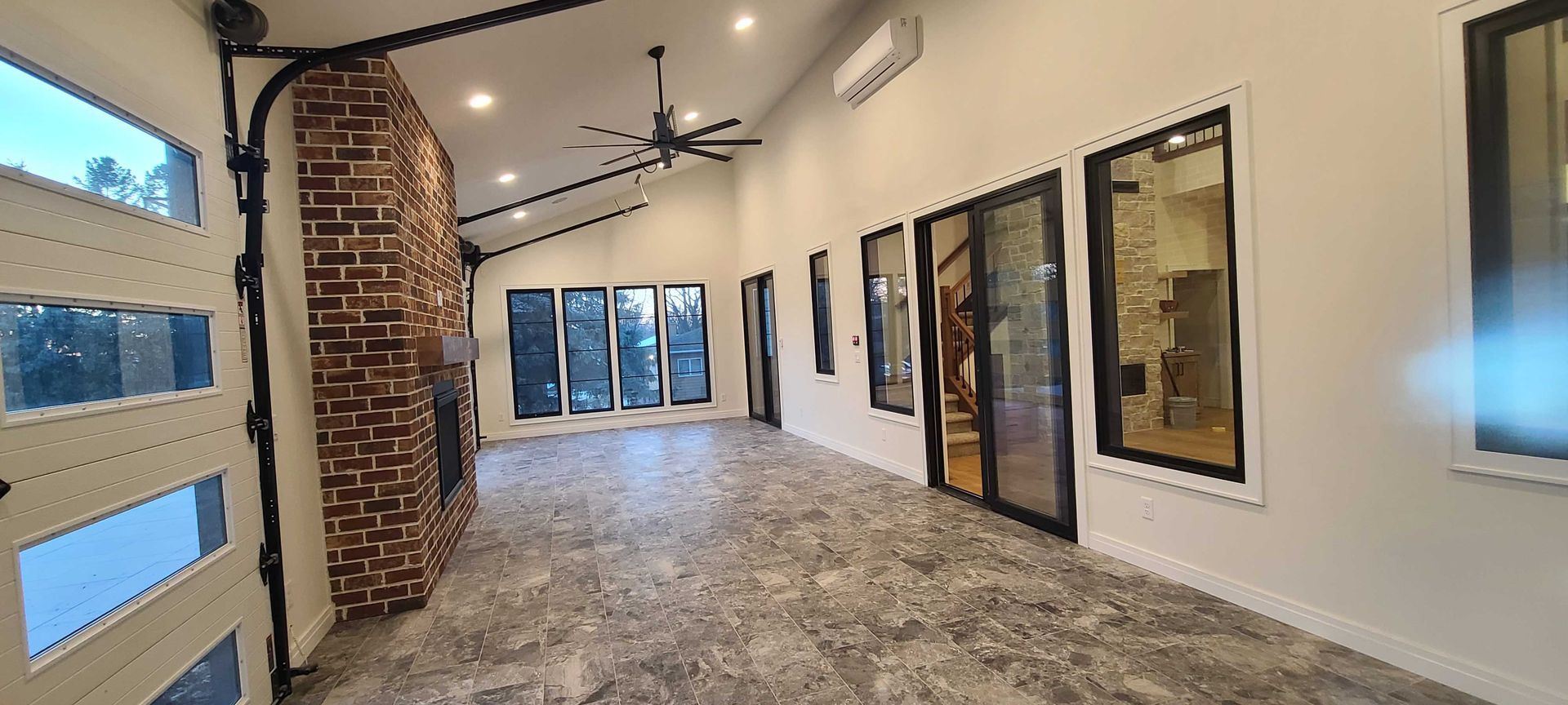 A long hallway with a lot of windows and a ceiling fan.