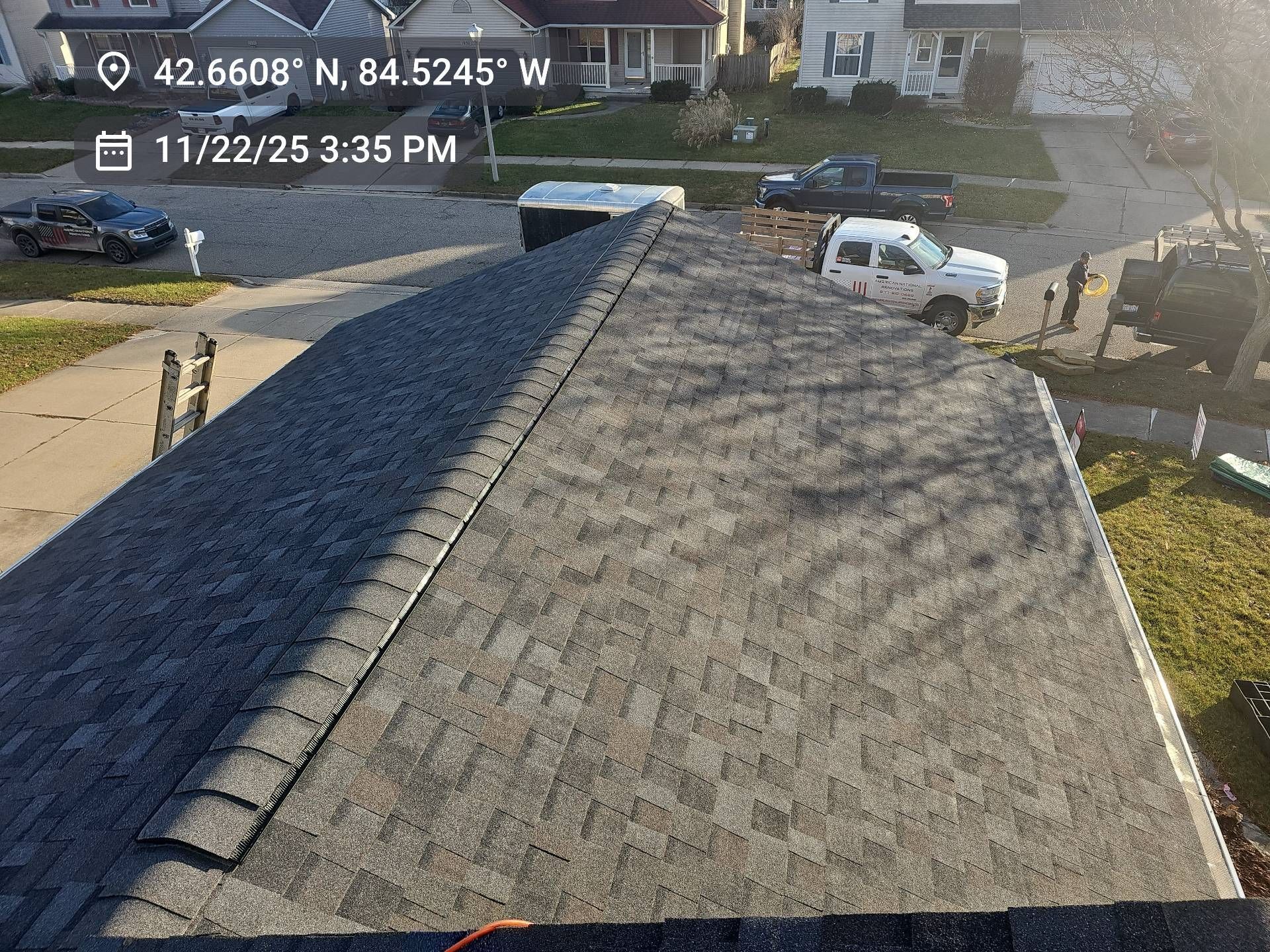A high-angle view of a roof being repaired, showing sections of new dark shingles adjacent to an older, lighter roof area.