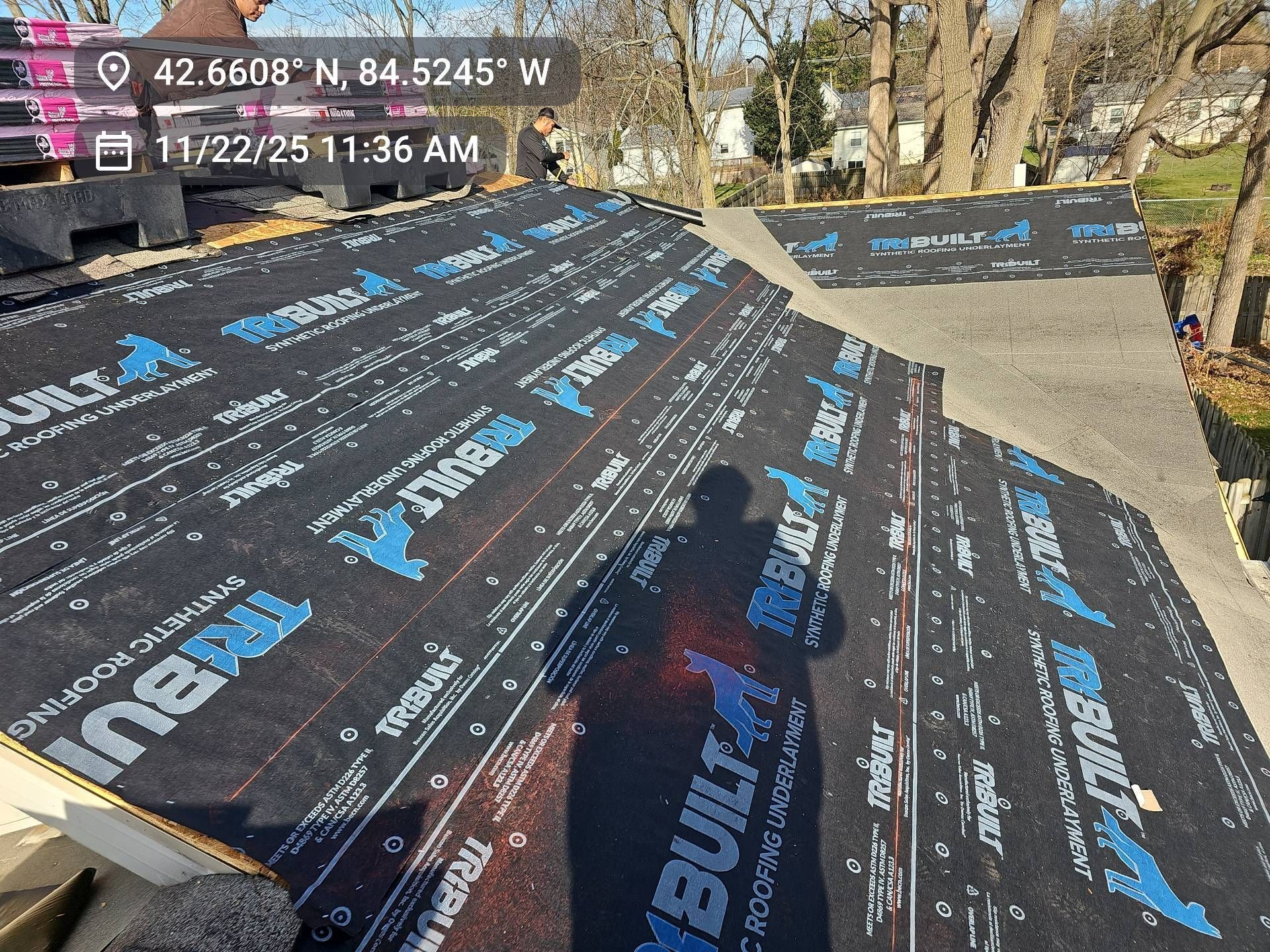 A high-angle view of a residential roof undergoing construction, covered with black Tri-Built synthetic underlayment.