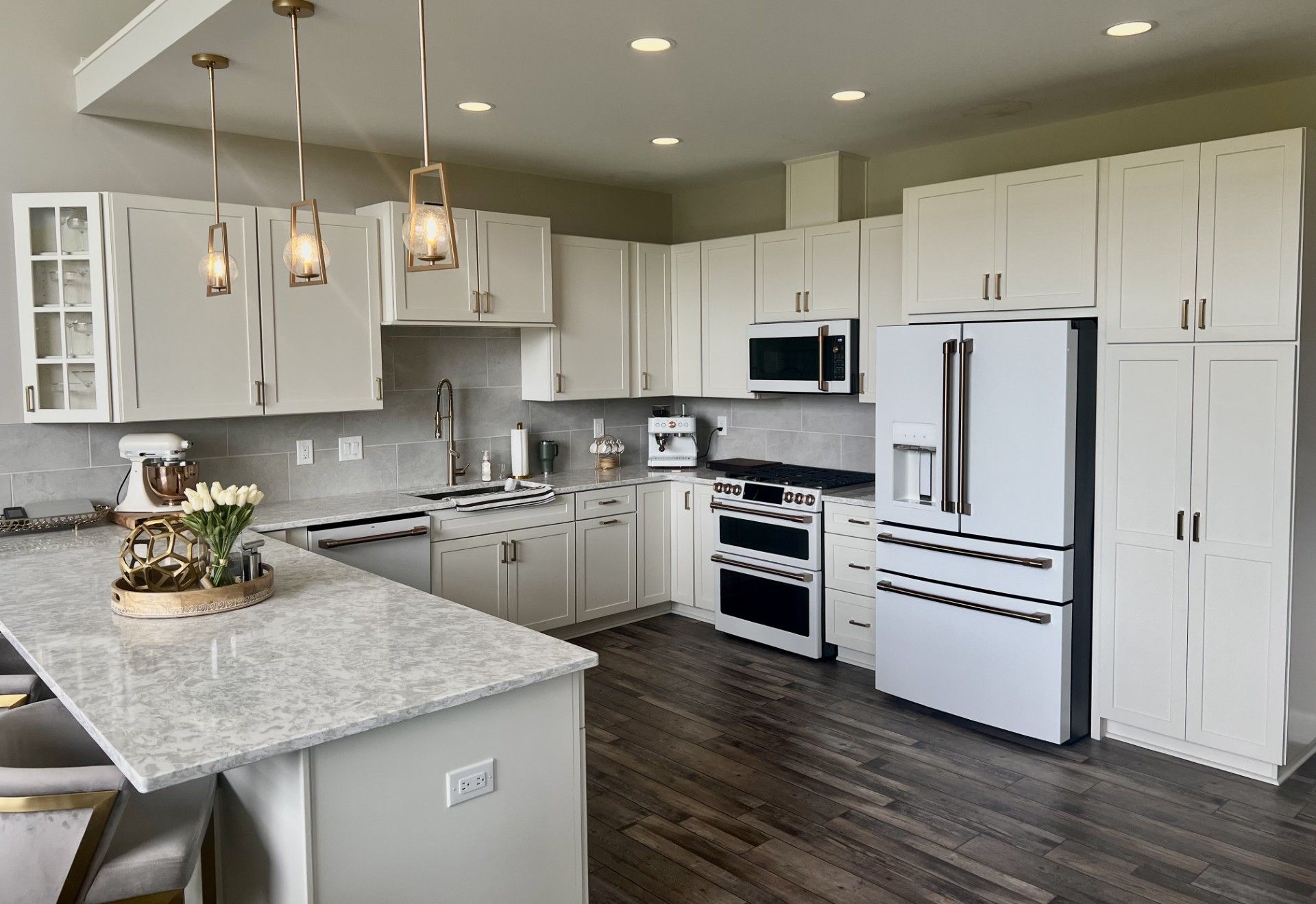 A kitchen with white cabinets , a refrigerator , a microwave , and a sink.