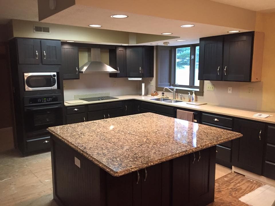 A kitchen with black cabinets and granite counter tops
