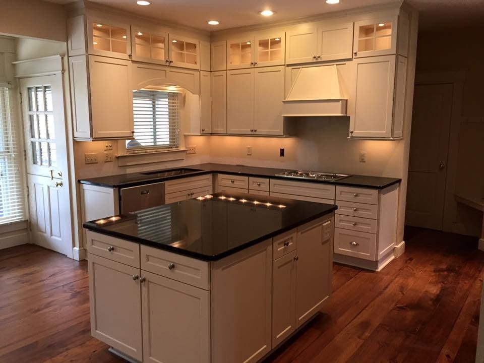 A kitchen with white cabinets and black counter tops