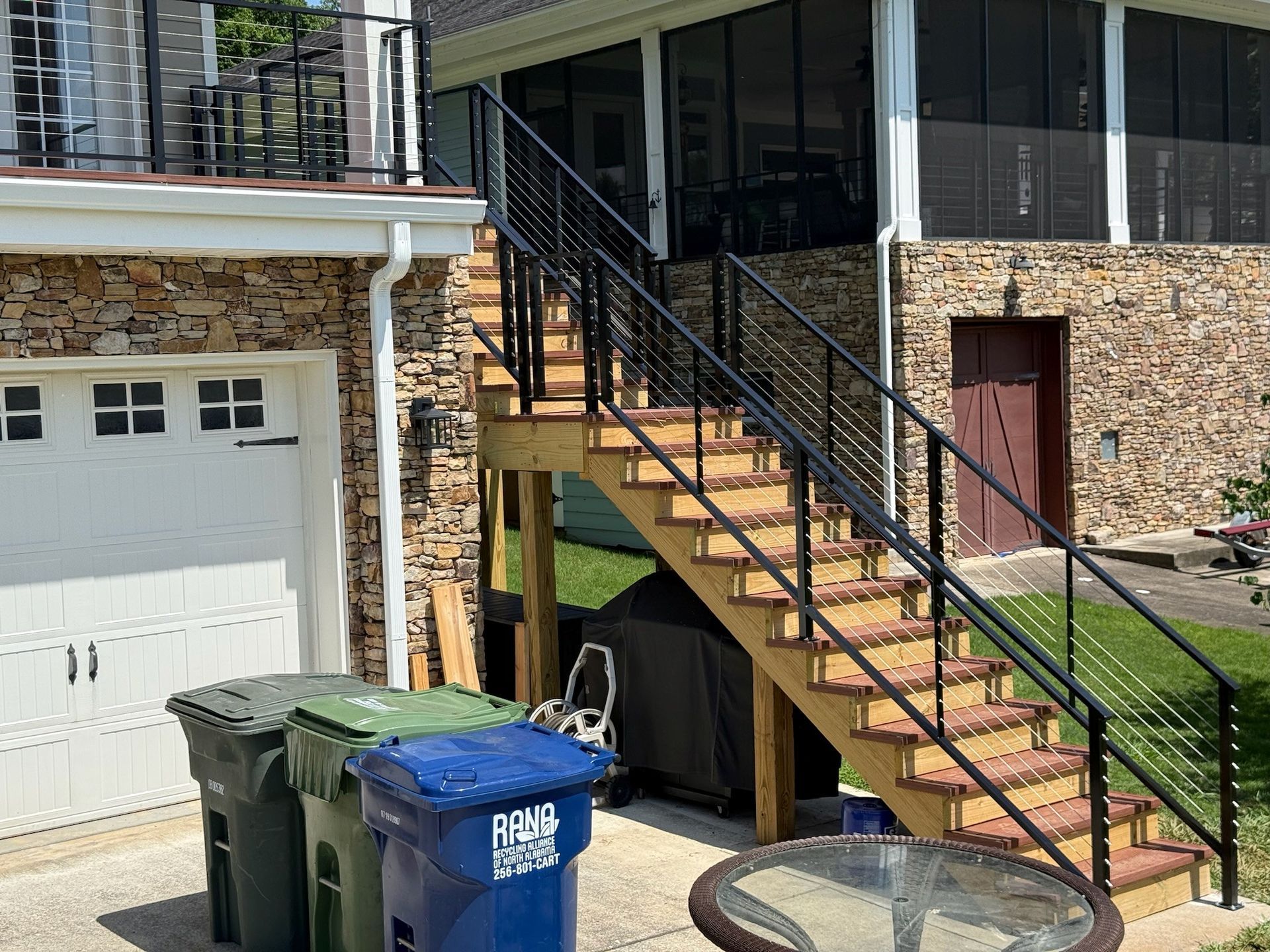 Exterior stairway beside a garage and trash bins on a brick house frontage