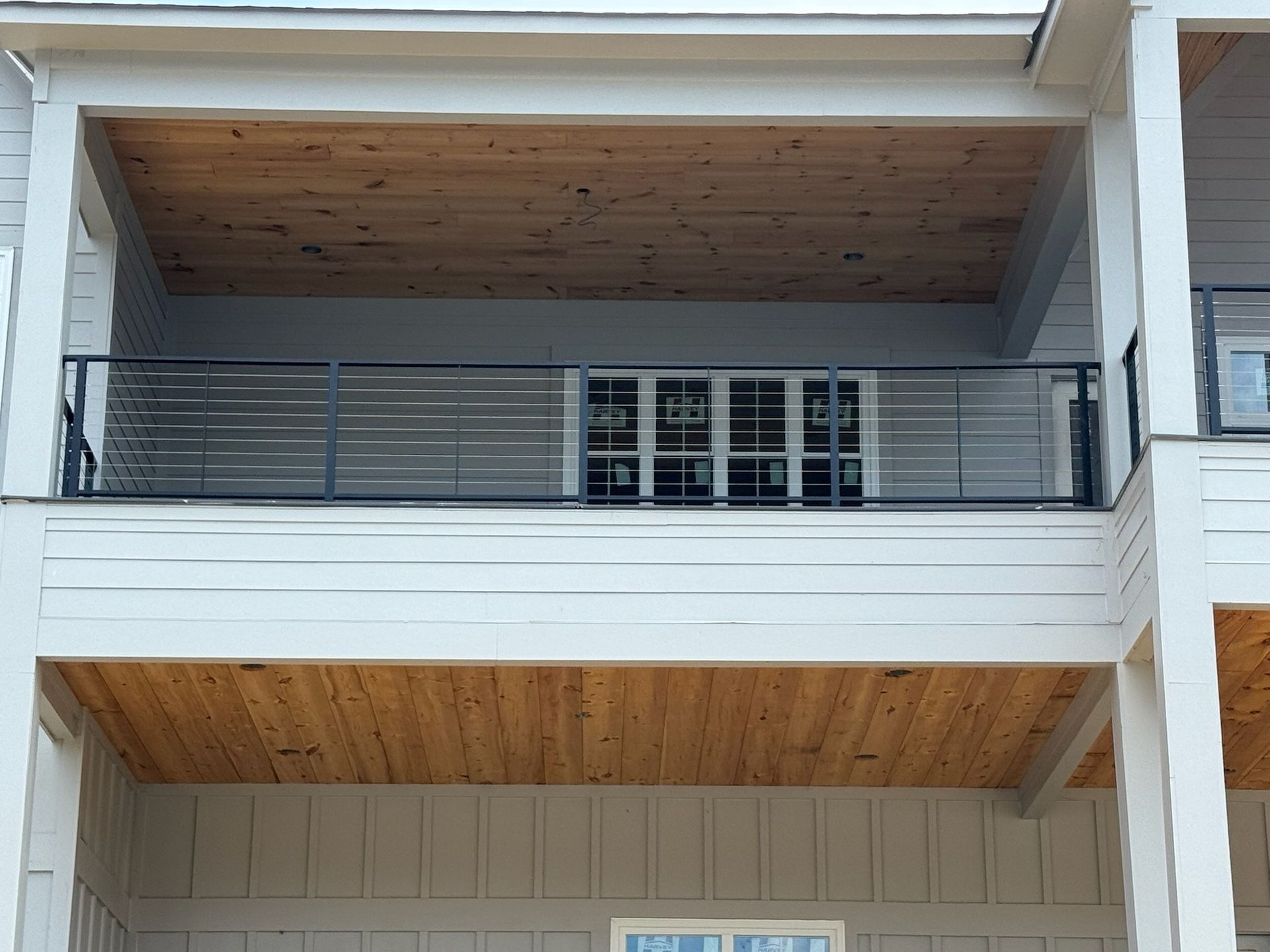 Balcony with gray railing, white siding, and wood-paneled ceiling on an apartment building