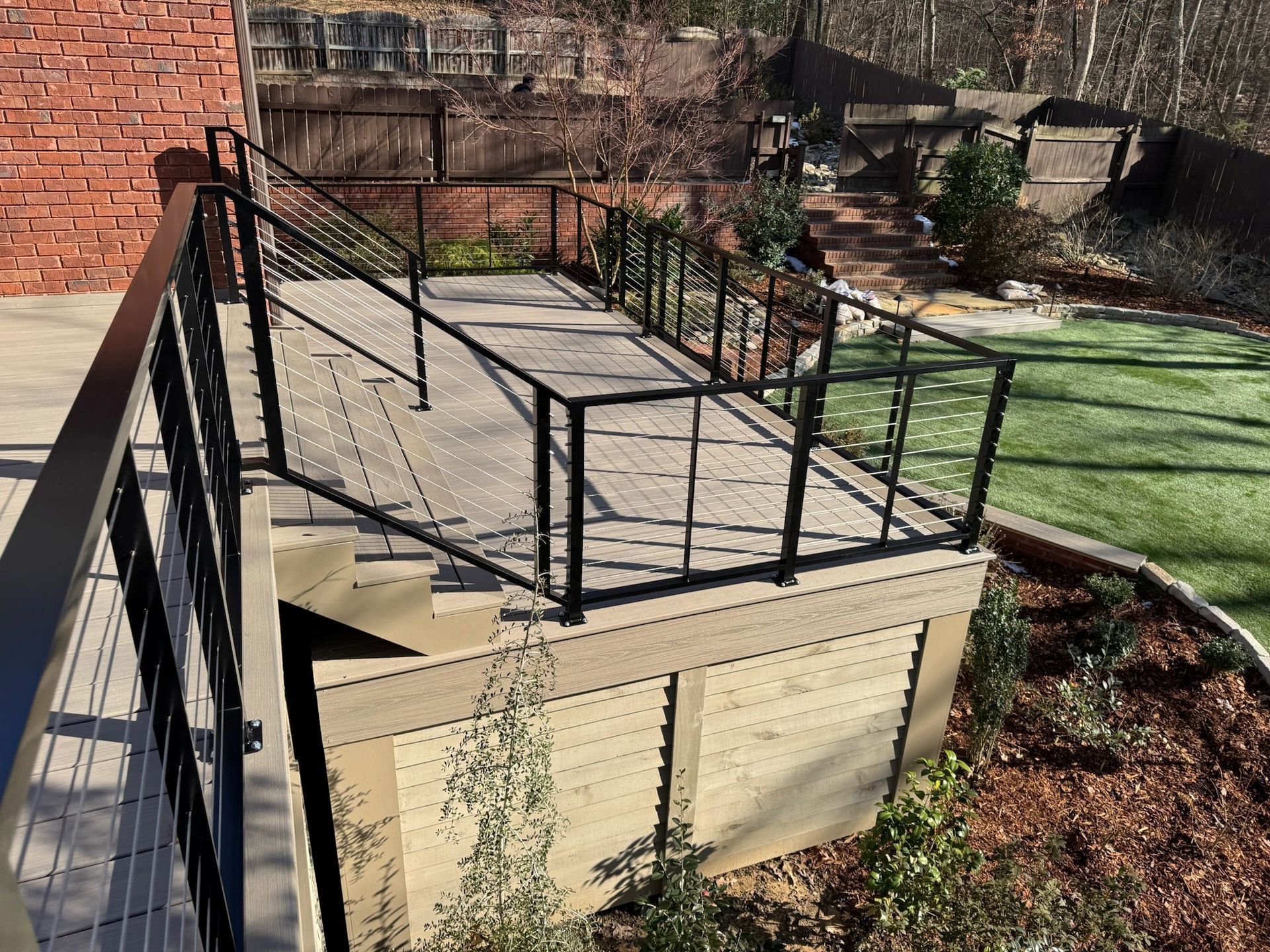 Black metal ramp and railing beside stone steps leading to a brick building and lawn