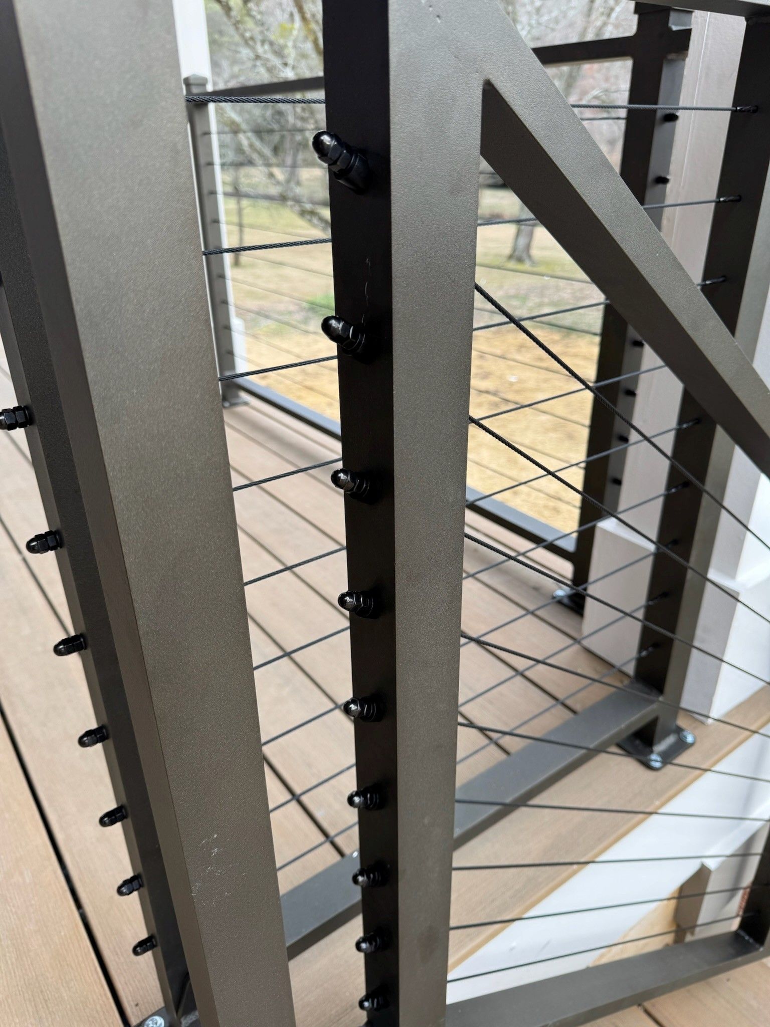 Interior stairwell with metal railings and cable balustrade beside large windows
