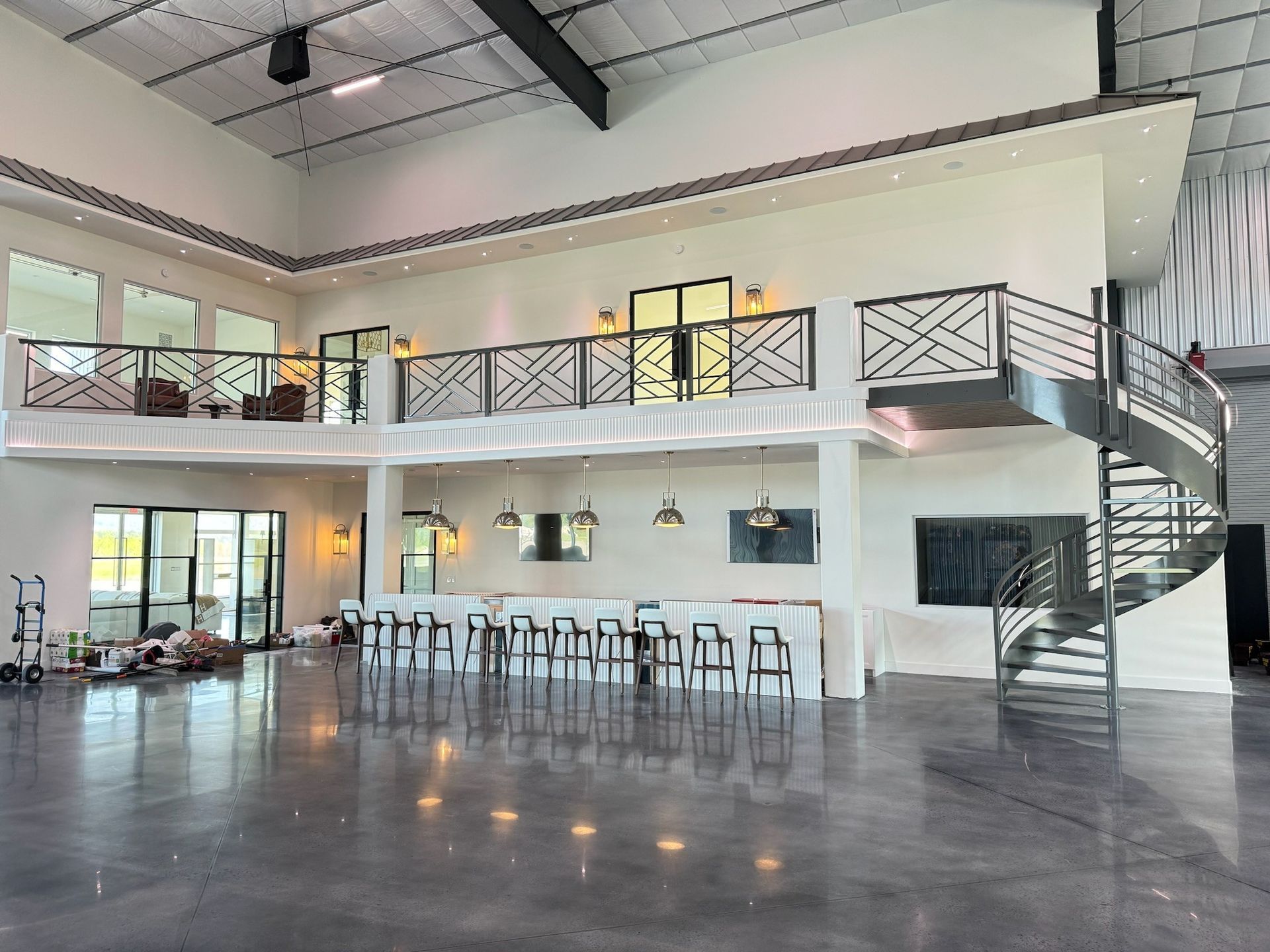 Spacious modern lobby with balcony railing, bar seating, and polished concrete floor