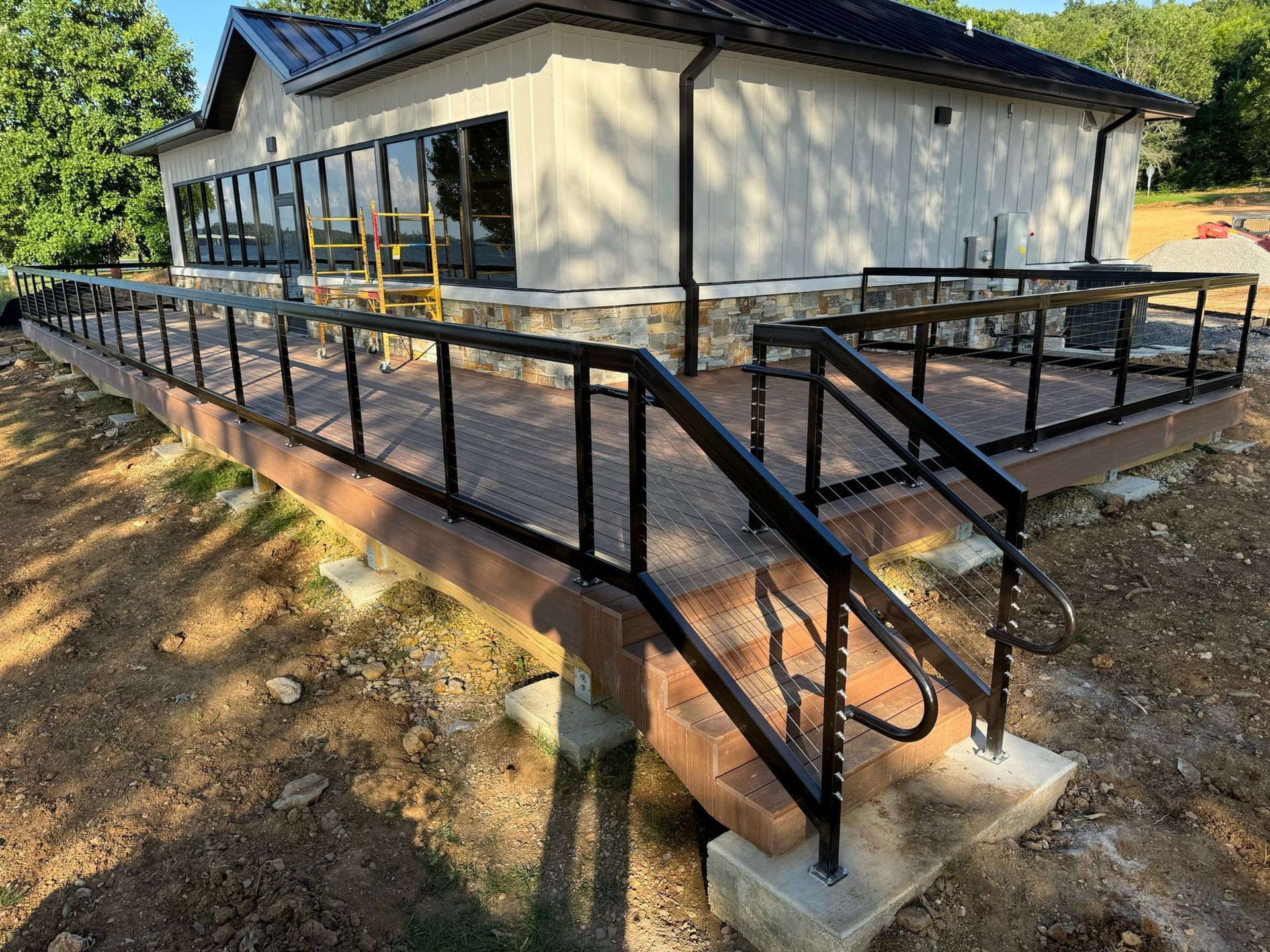 Accessible ramp and stairs with black railings beside a light-colored building.
