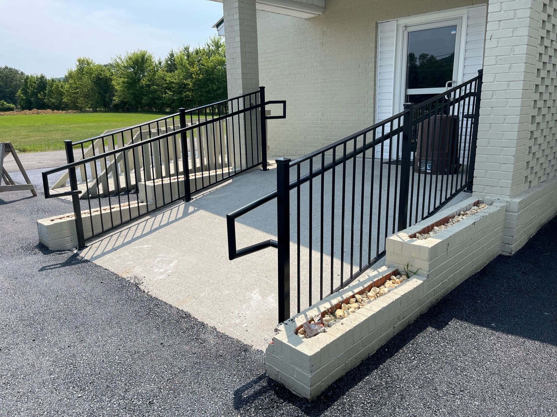 Concrete wheelchair ramp with black railings leading to a white building entrance