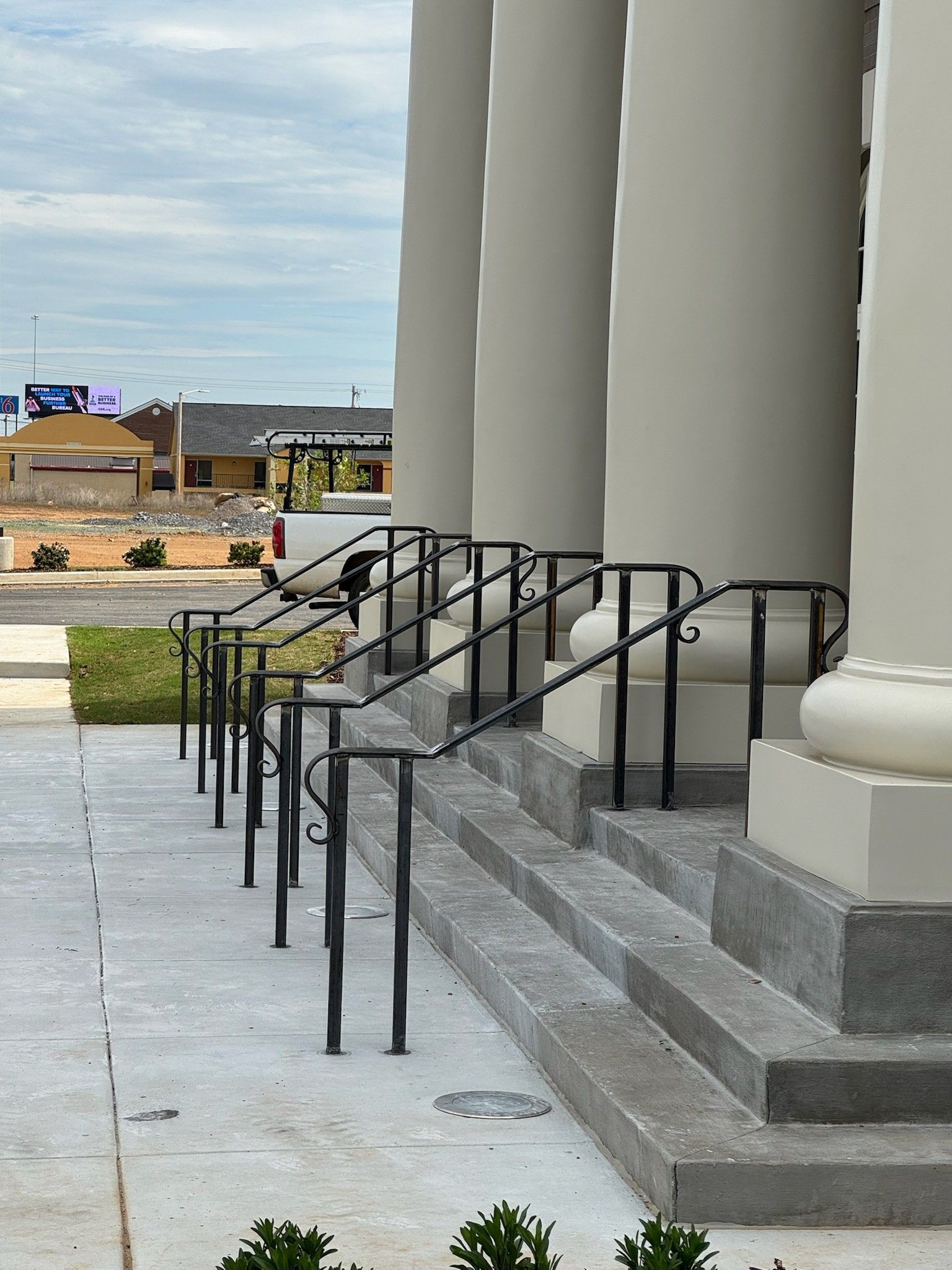 Accessible ramp and steps leading to a building entrance with black railings and large columns