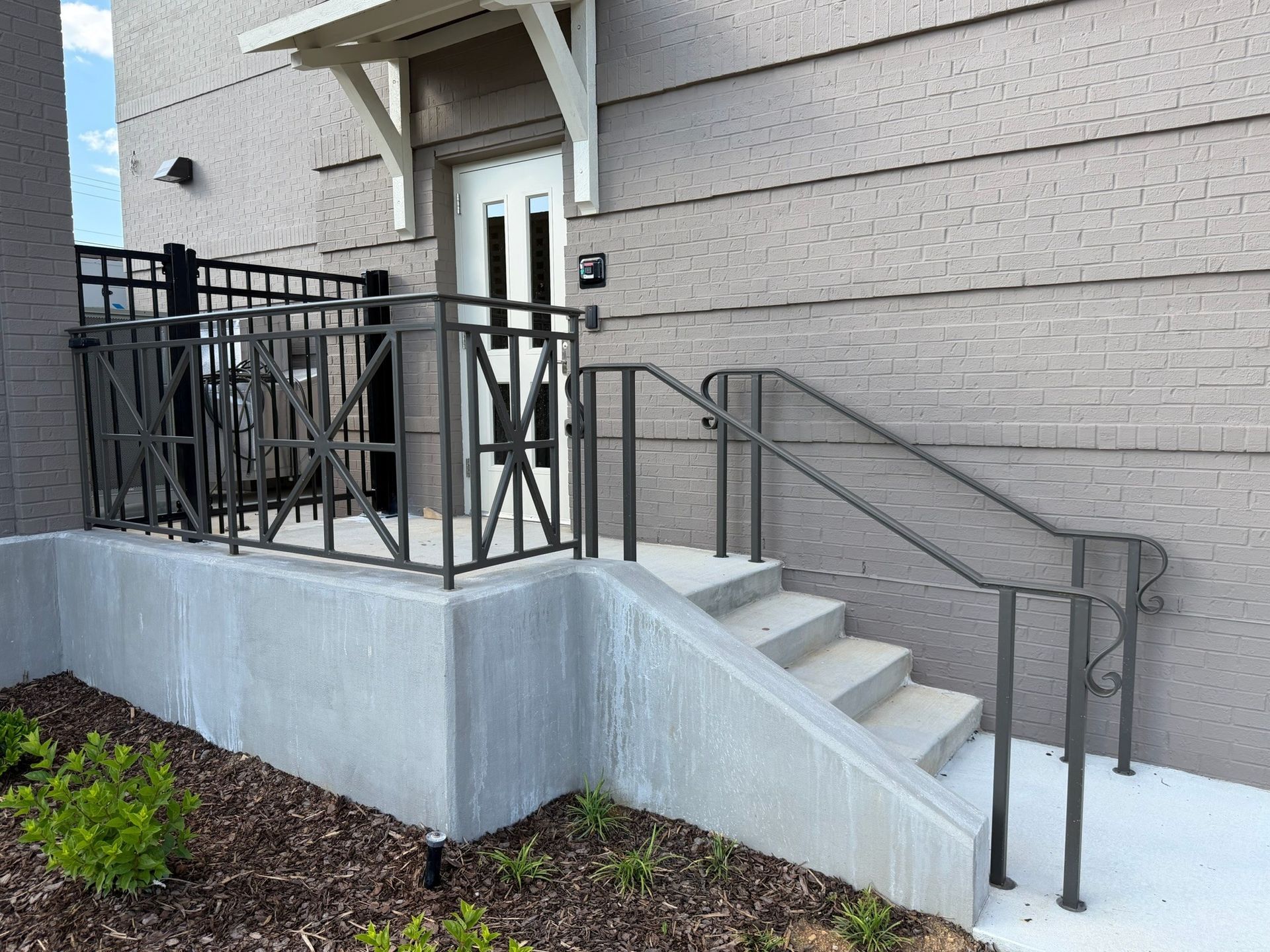 Accessible concrete steps and ramp with black metal railings leading to a building entrance