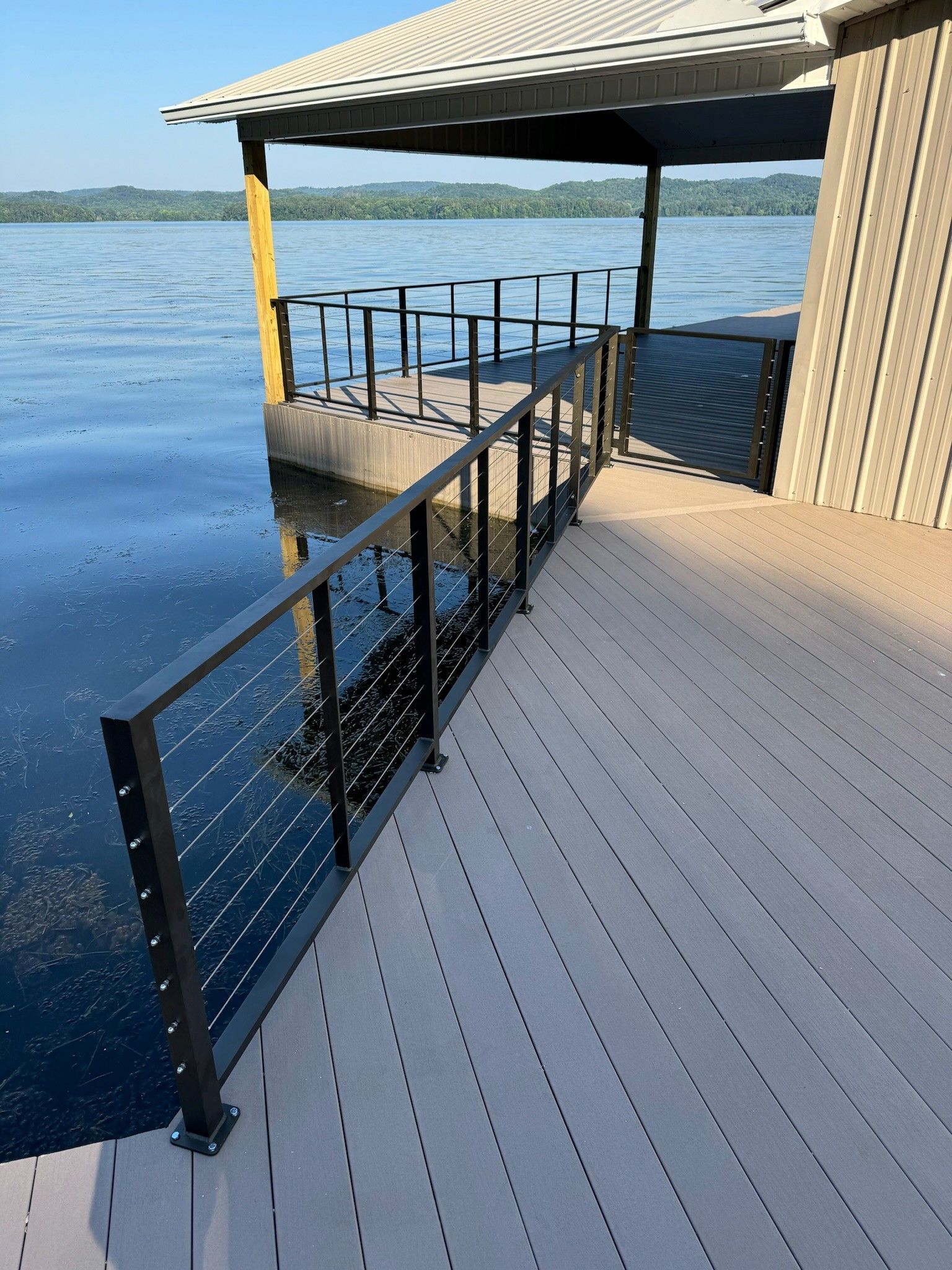 Covered lakeside dock with black railings and blue water