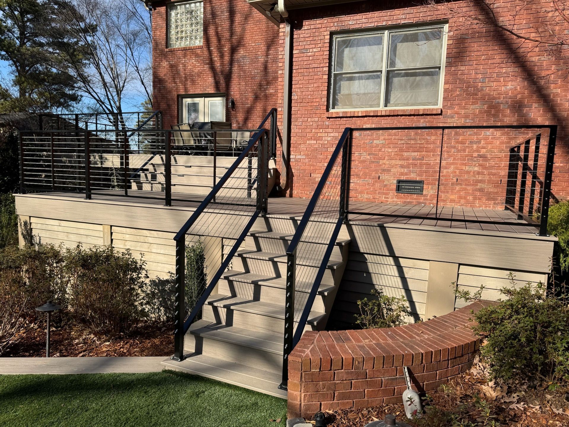 Brick building entrance with concrete stairs, black railings, and a raised accessible platform.