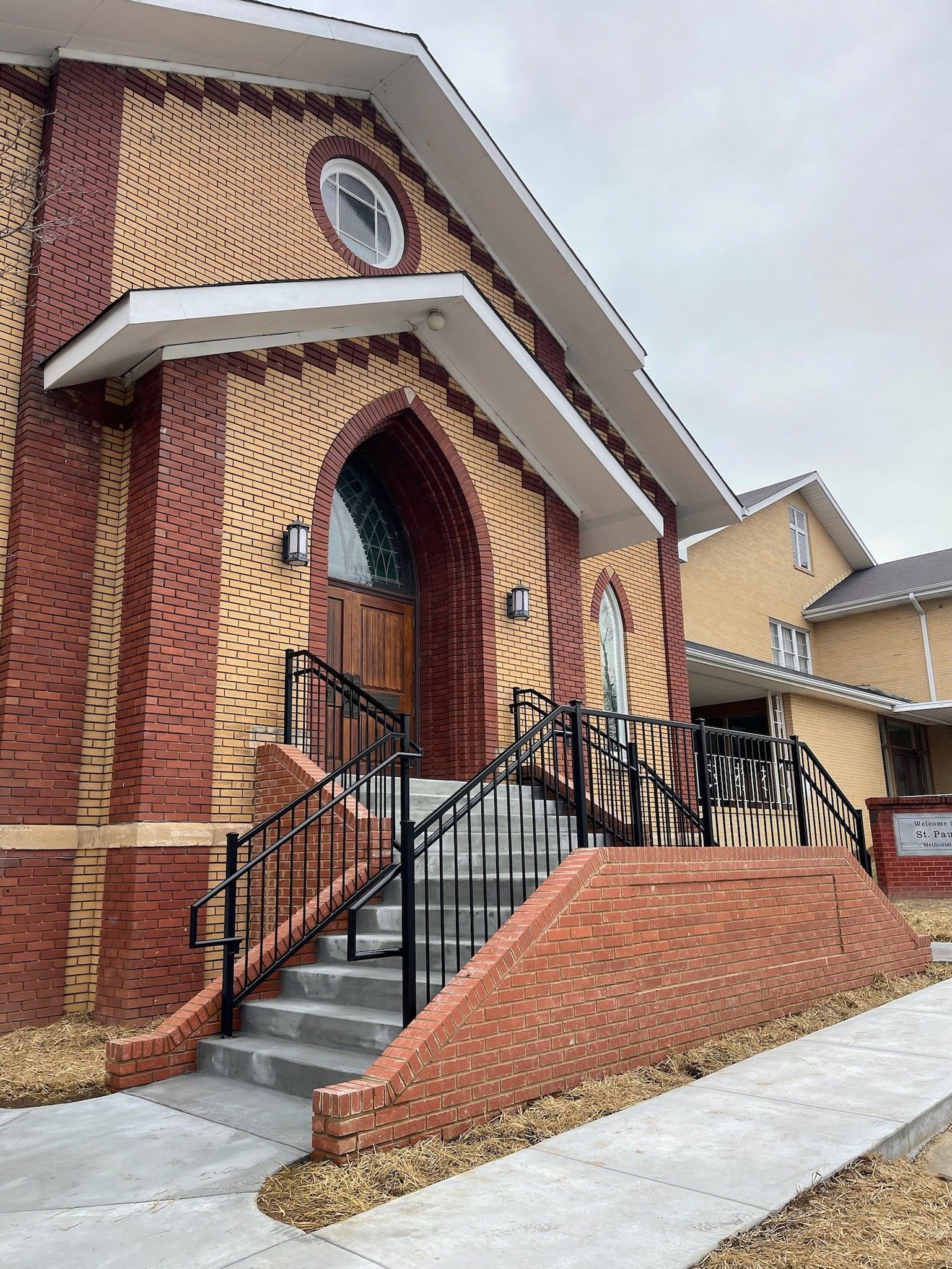 Brick building entrance with stairs, black railings, and a white awning over the doorway