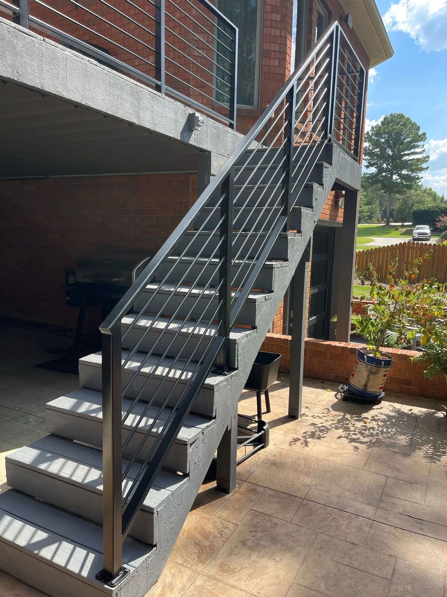 Black metal outdoor staircase with railings beside a brick building and patio.