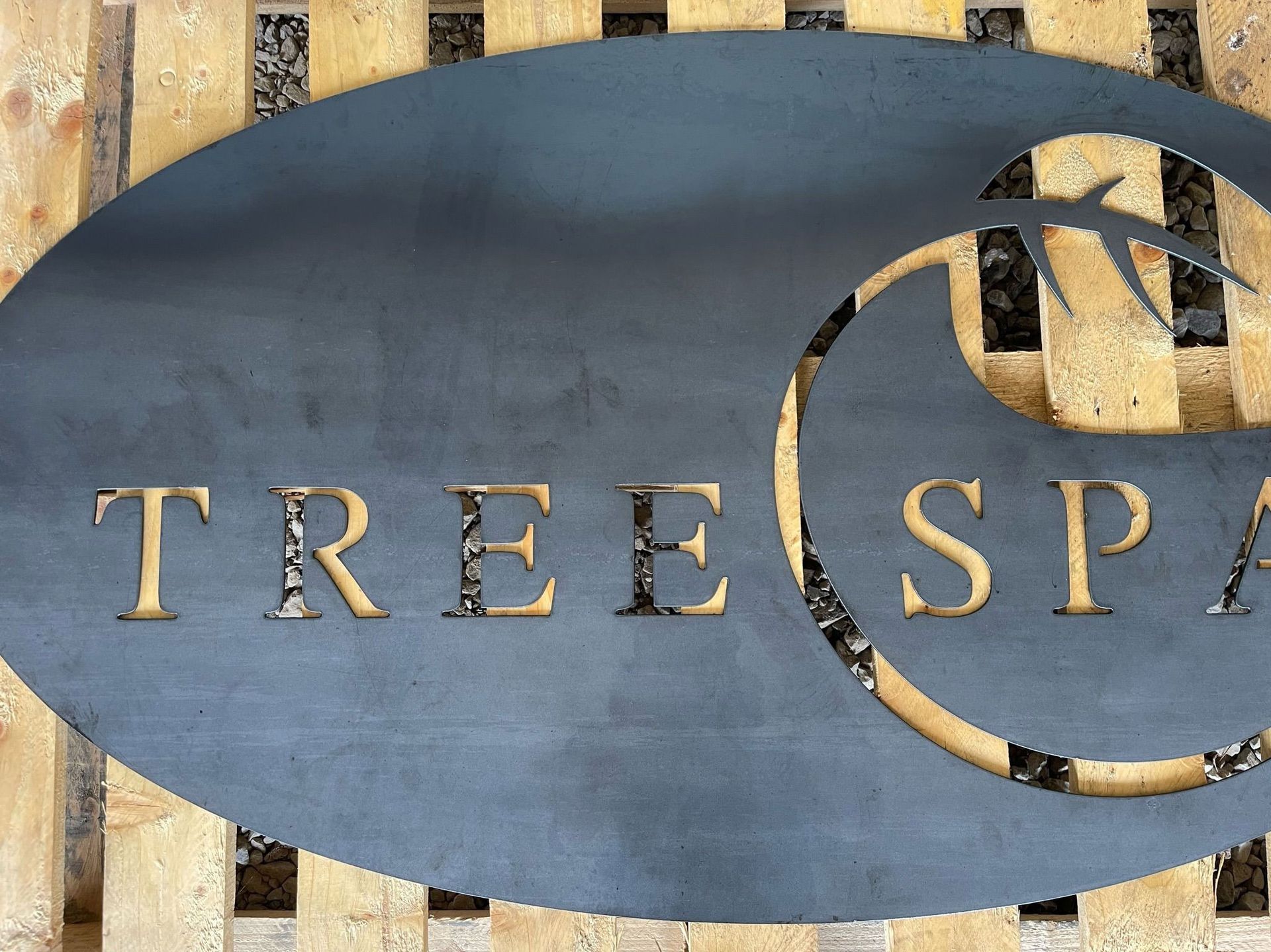 Metal sign reading “TREESPA” on a wooden fence background
