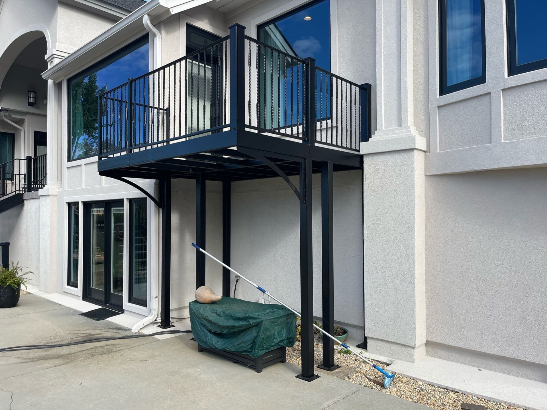 Backyard view of a white apartment building with a black metal balcony and staircase armature