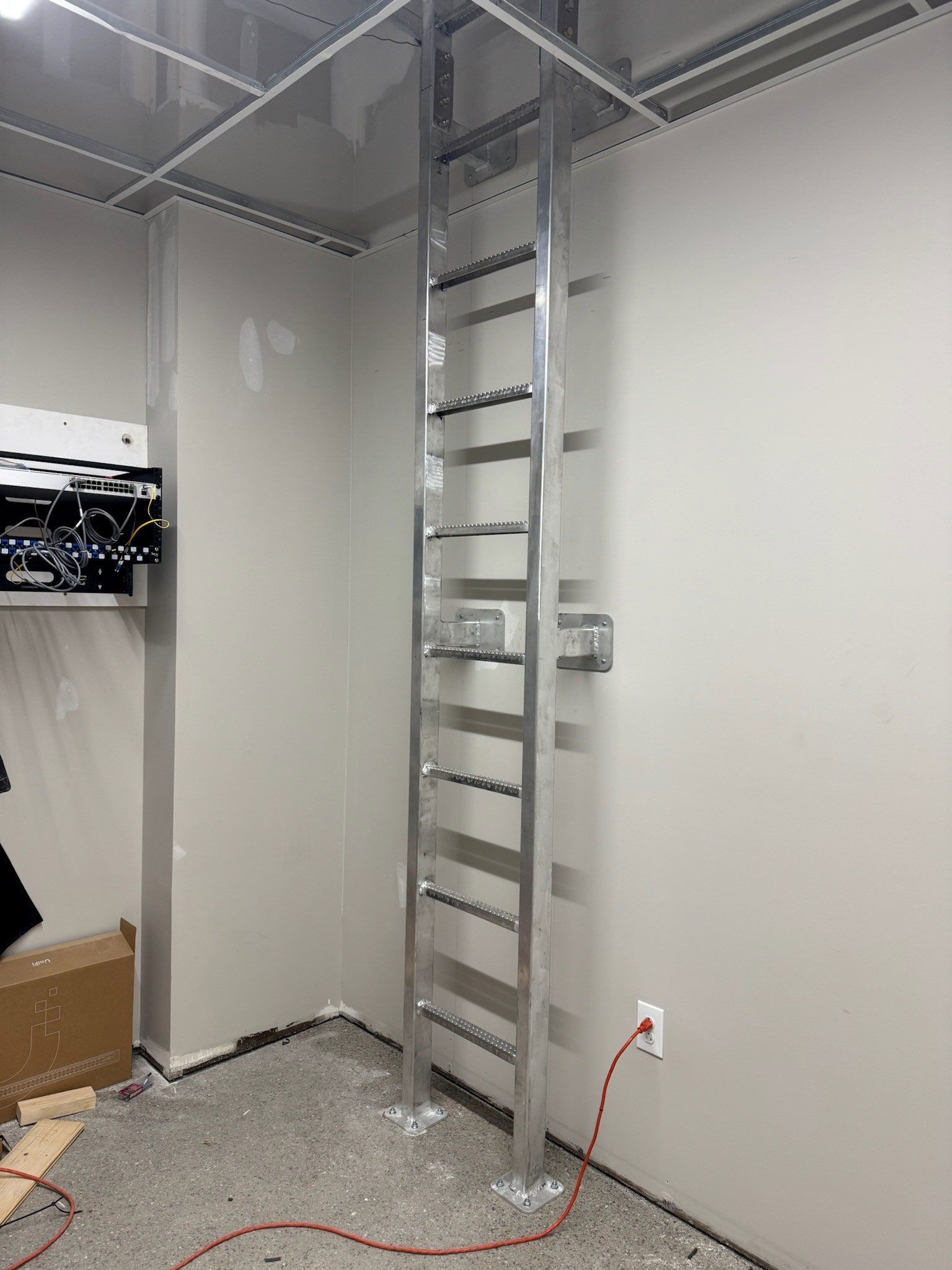 Interior room with unfinished walls, a metal ladder, exposed wiring, and a cardboard box on the floor.