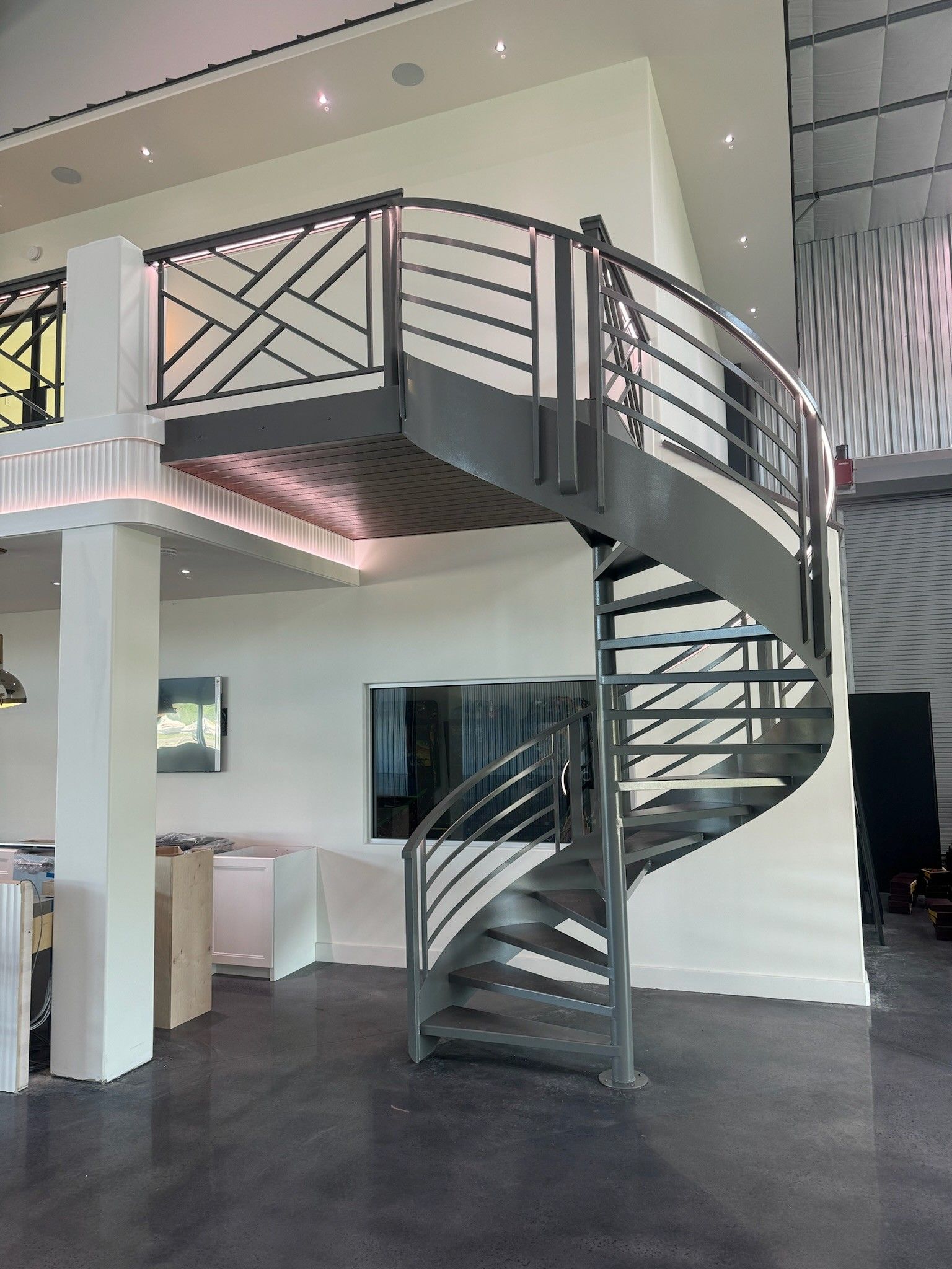 Modern indoor spiral staircase with black metal railings in a bright loft-style room