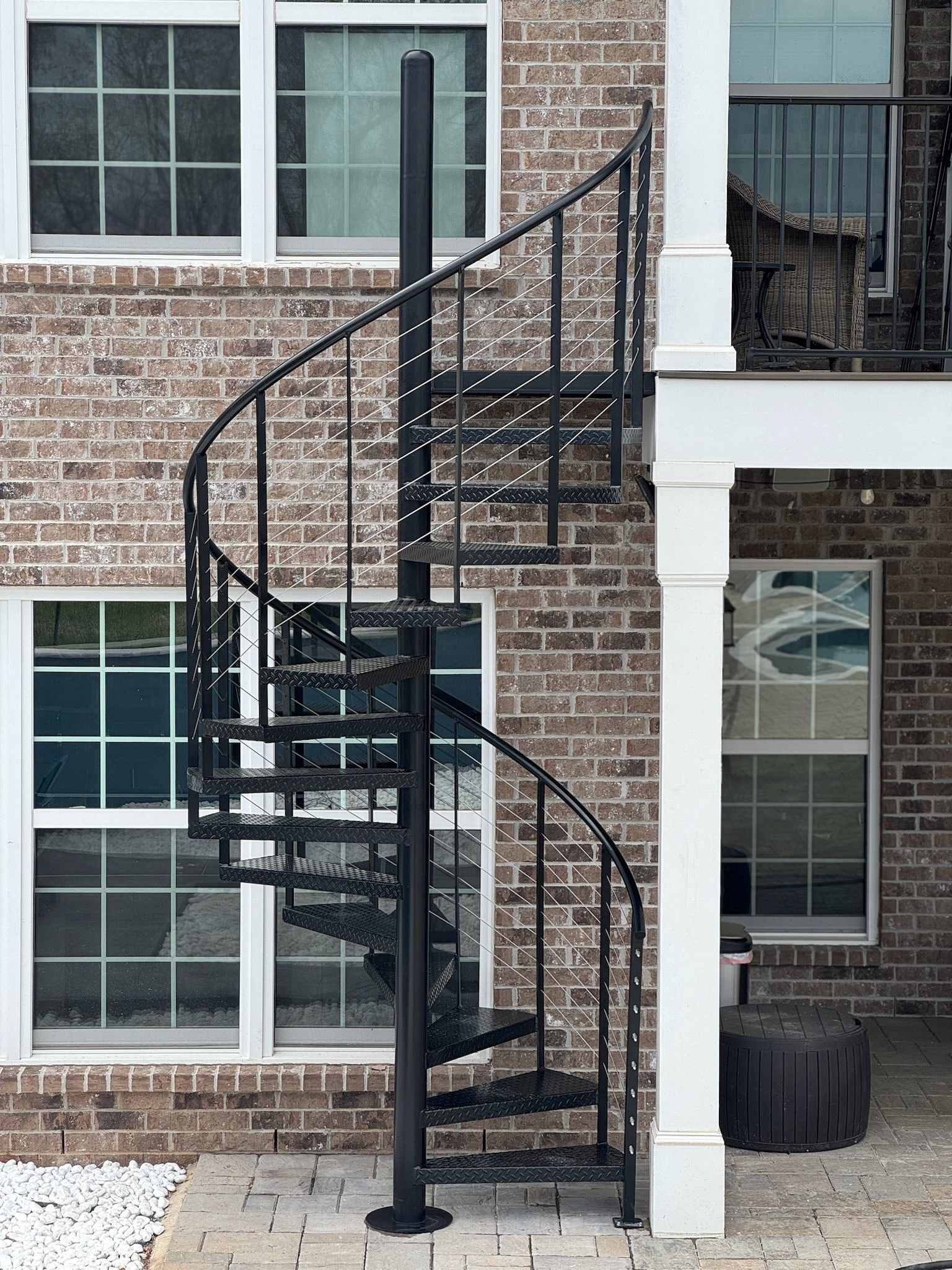 Black spiral metal staircase attached to a brick building exterior.
