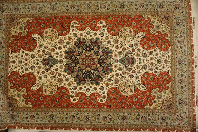 Ornate red and cream patterned rug with a central floral medallion and border