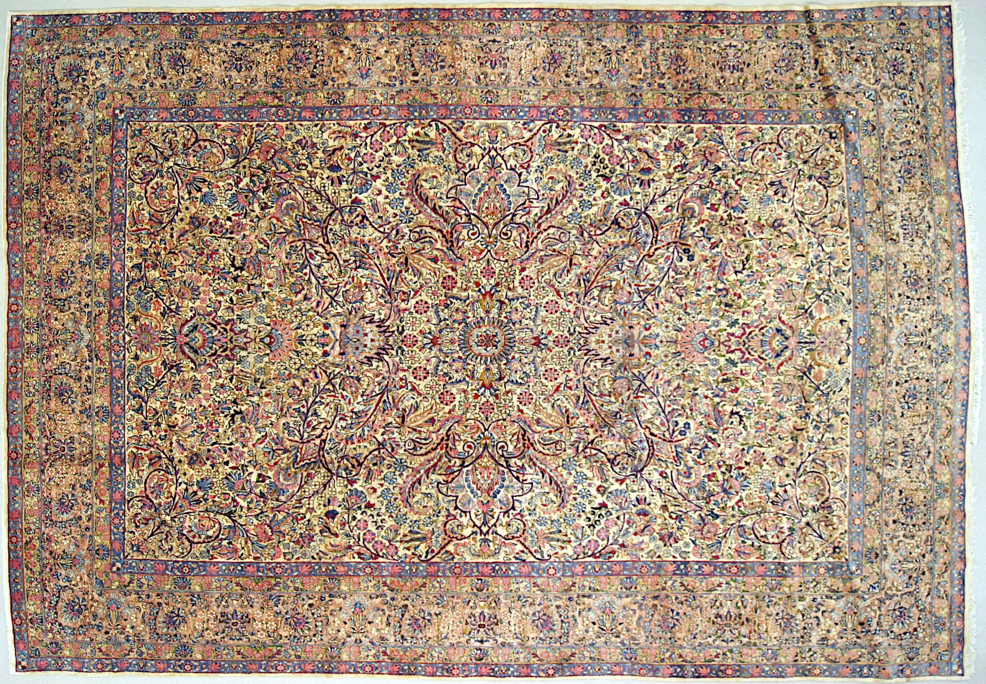 Abstract multicolored patterned textile rug with a beige border and dense red, blue, and gold motifs