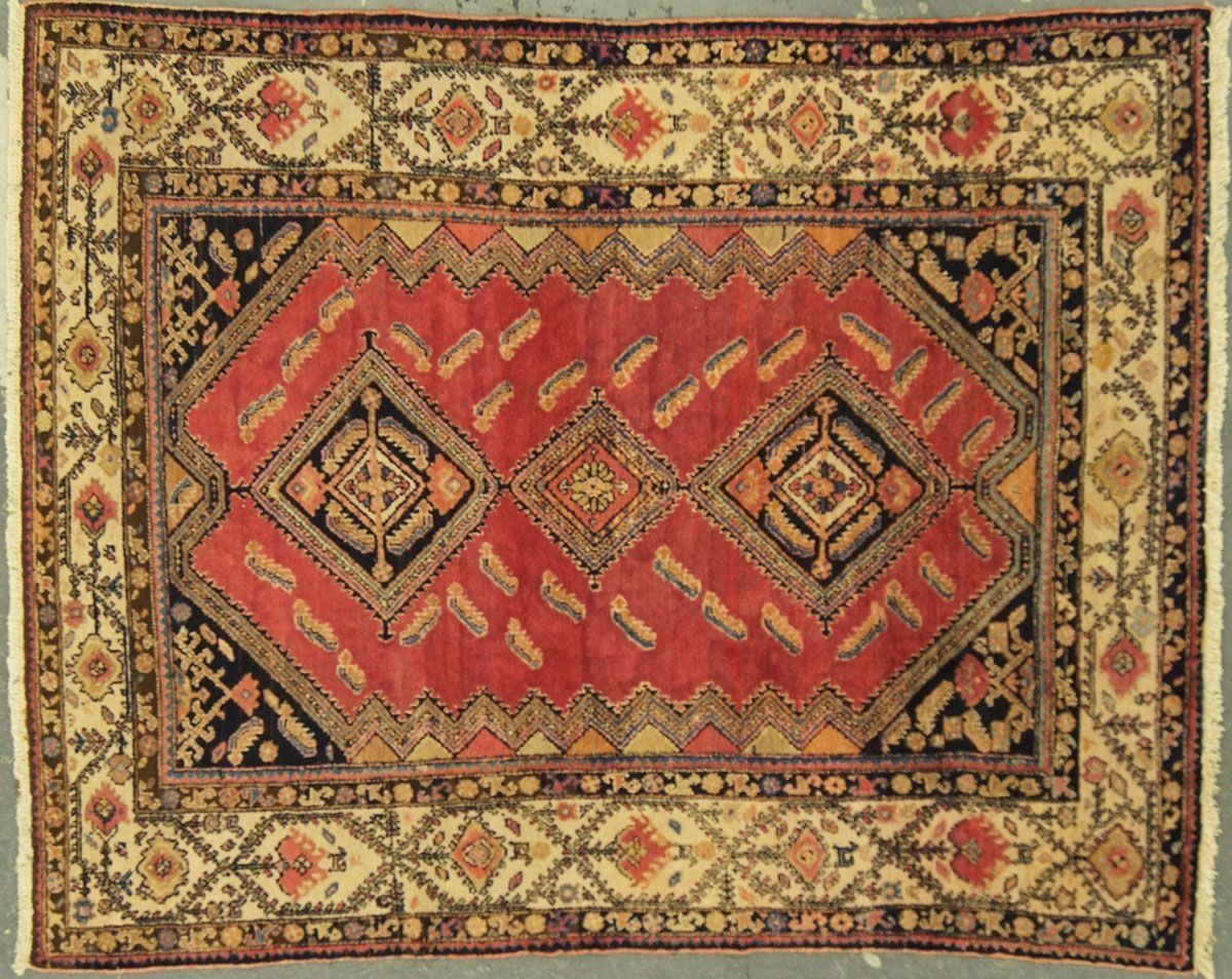 Red and black rectangular oriental rug with floral border and diamond pattern.