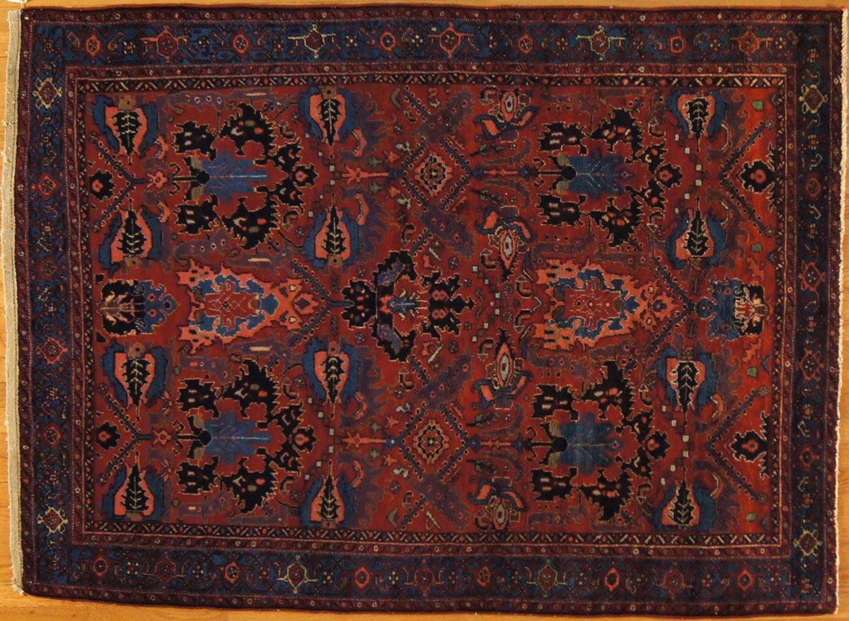 Red and blue oriental rug with central floral motifs and border.