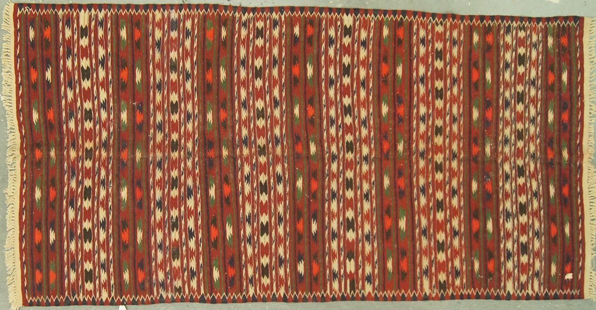 Brown and red patterned rug with vertical stripes and fringed edges.