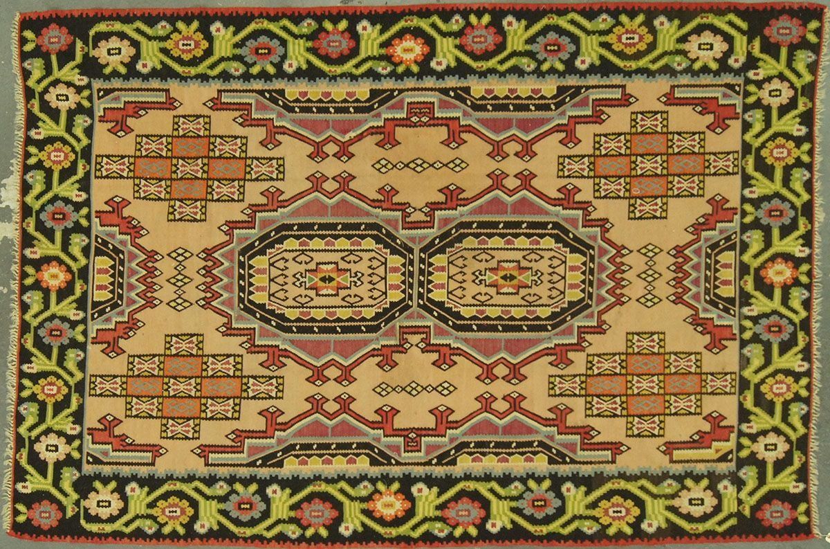 Oriental rug with geometric patterns in beige, brown, red, black, green, and yellow.