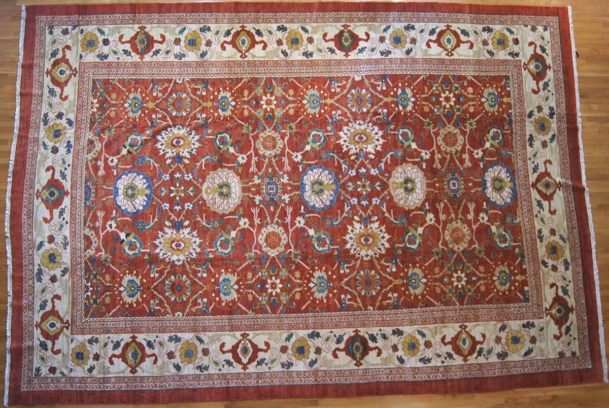 Red rectangular oriental rug with floral and geometric patterns, cream border.