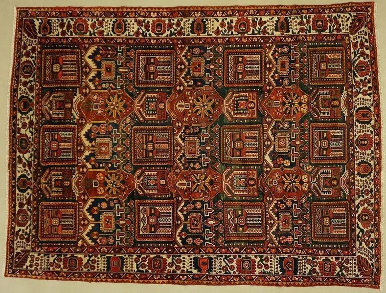 An antique rectangular rug with intricate red, brown, and ivory geometric patterns.
