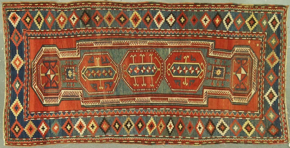 Rectangular red, blue, and gray oriental rug with central geometric medallions and diamond border.