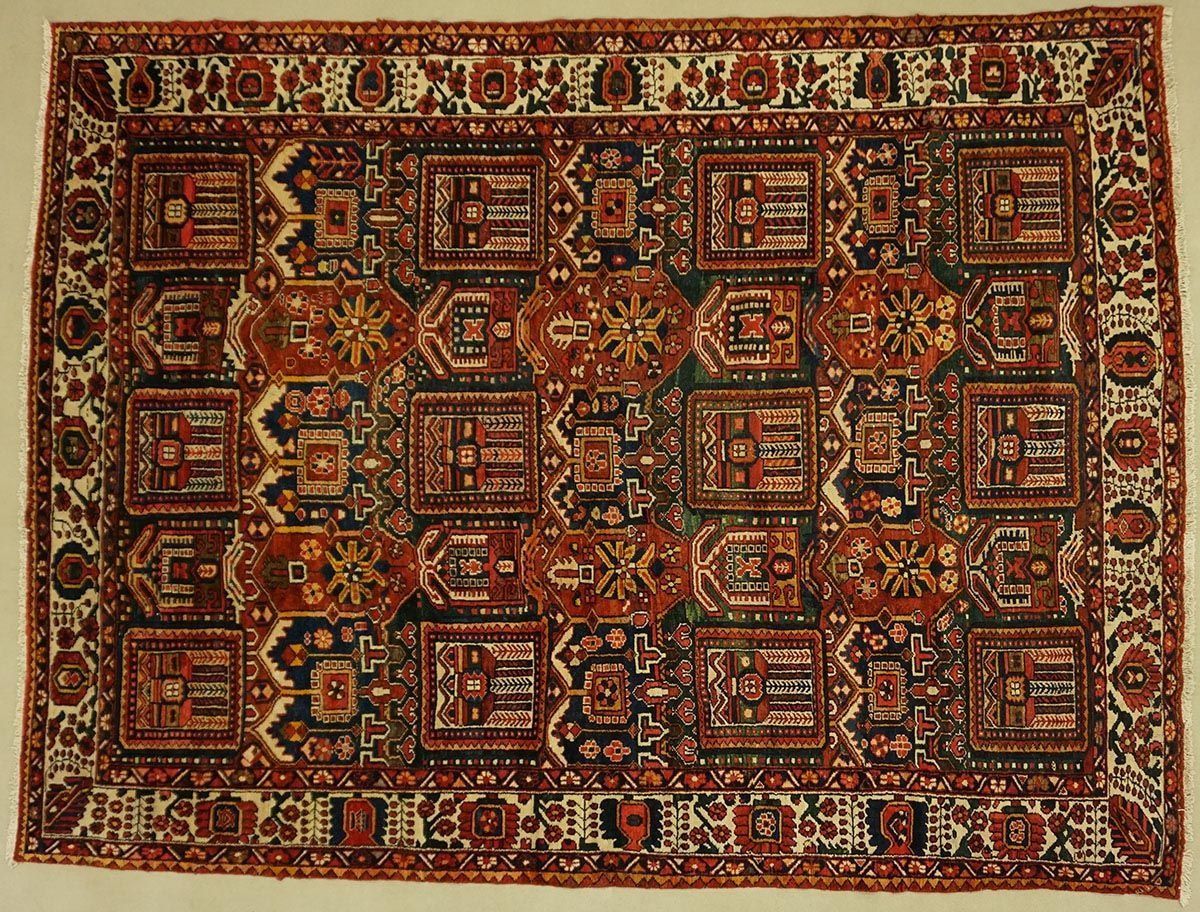 Red and dark blue Persian rug with geometric patterns and floral border.
