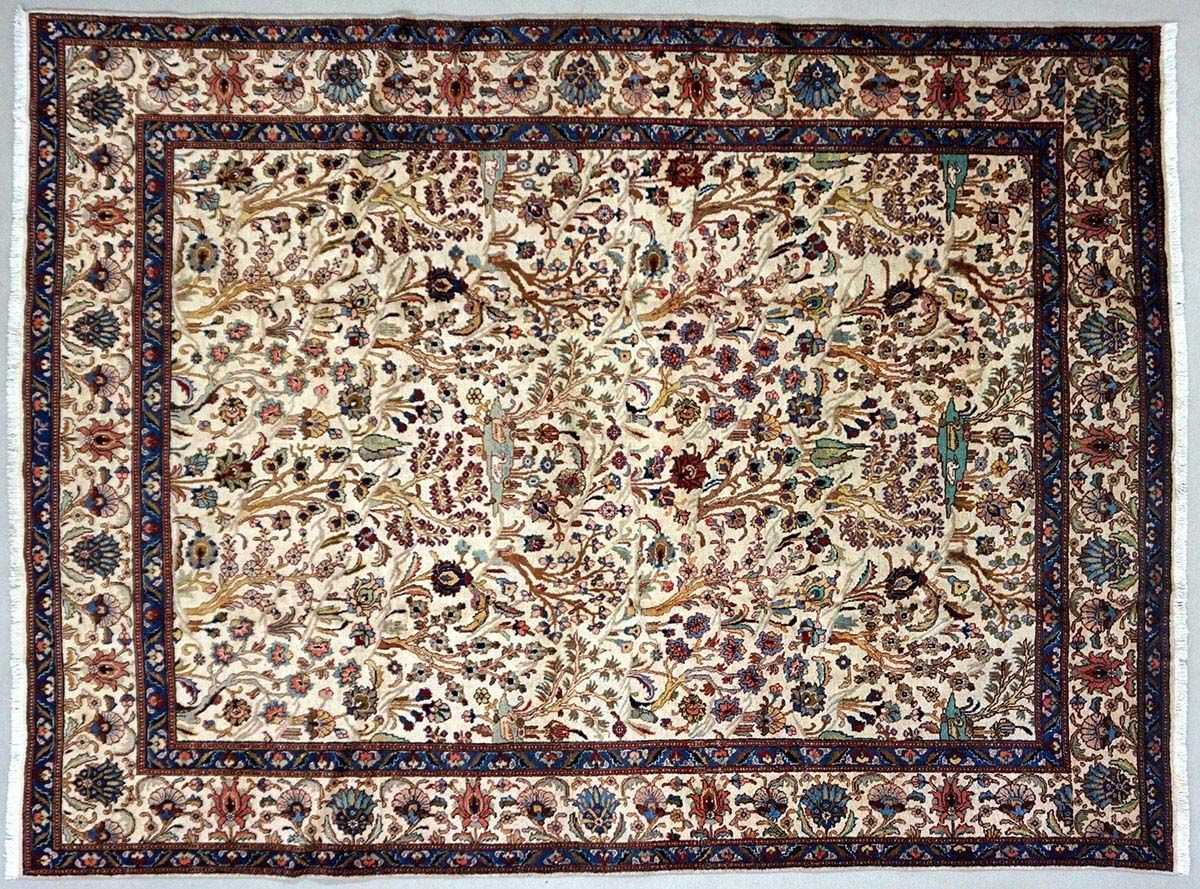 Cream-colored rectangular oriental rug with floral and bird motifs, navy blue border, and tassels.